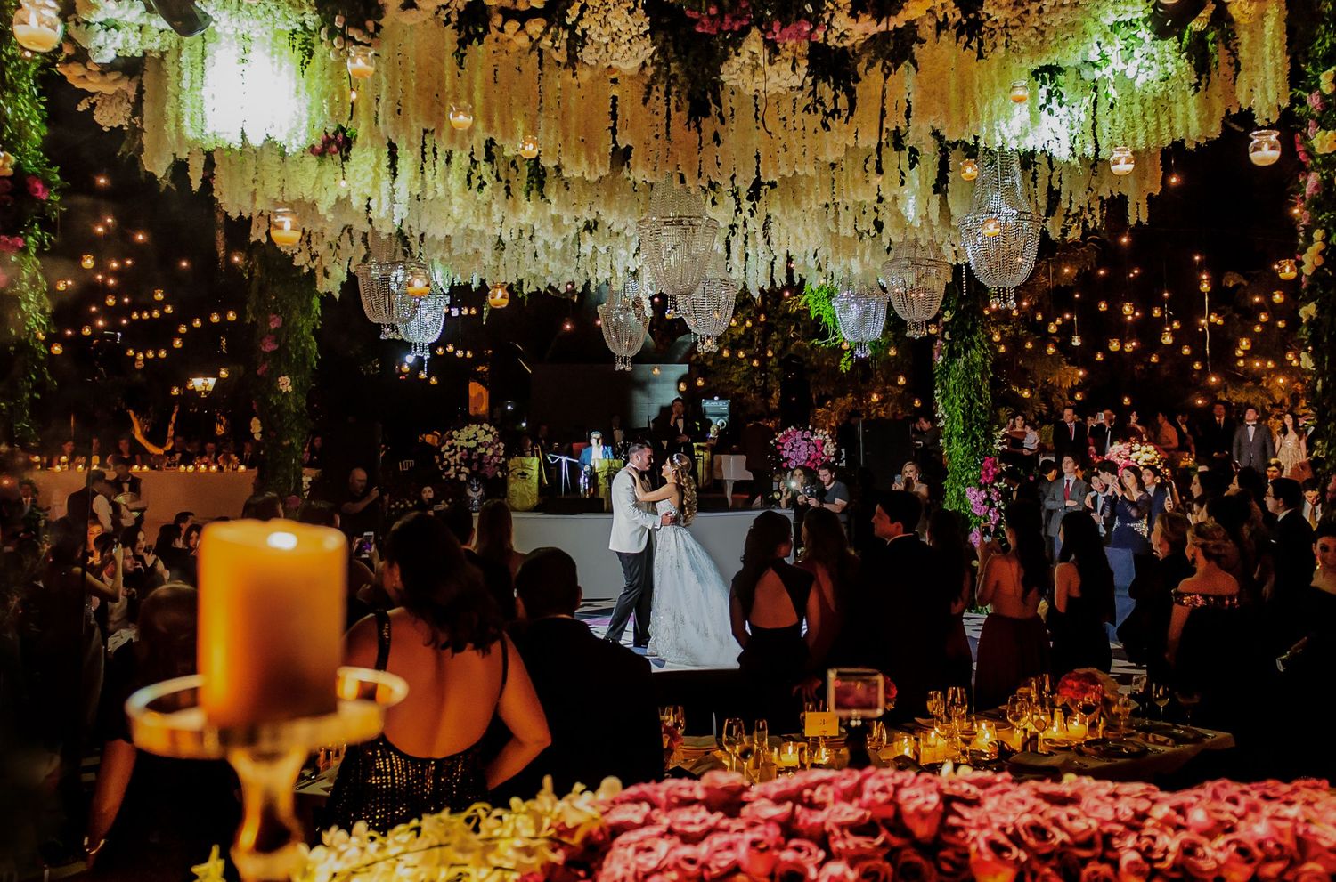 Wedding reception venue decorated with elegant hanging floral arrangements and warm lighting.
