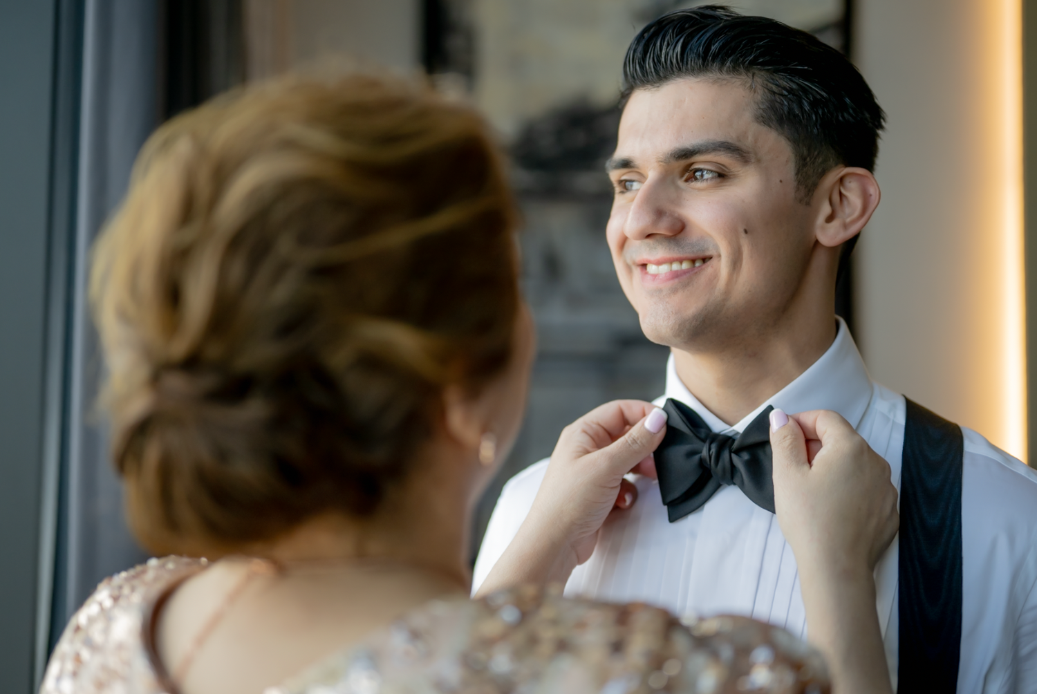 Professional wedding photography session shows couple in formal attire sharing intimate moments by large windows.