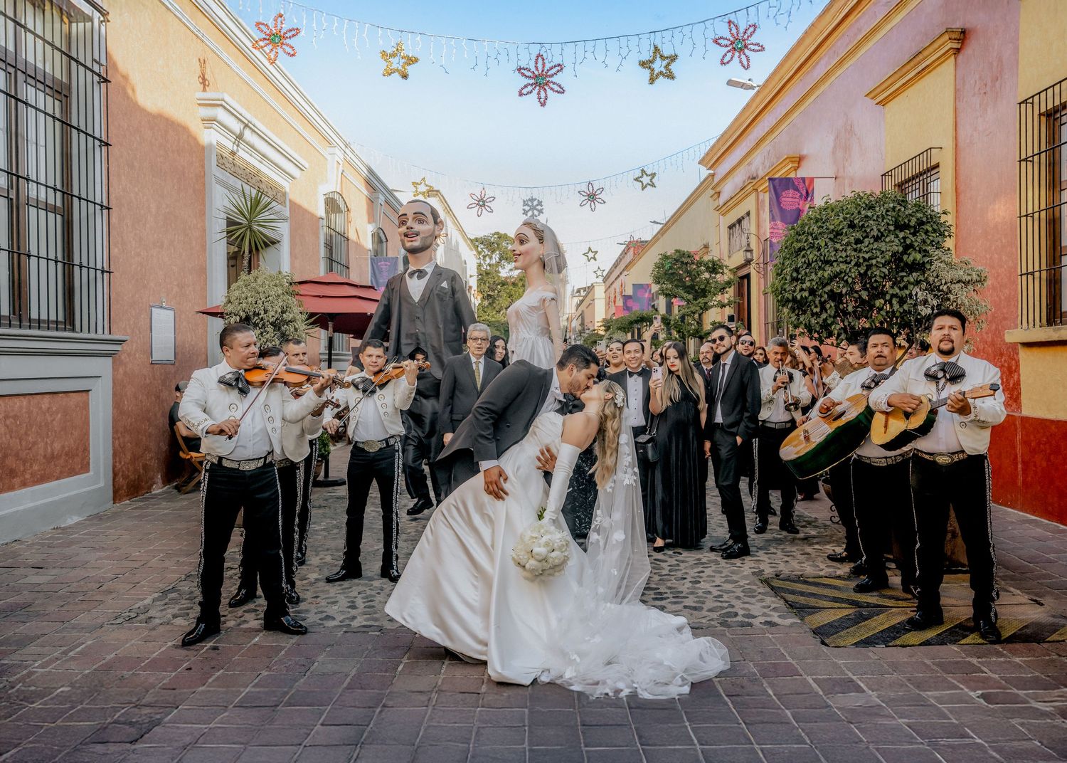 A festive wedding celebration in a colorful Tequila street with mariachi band and decorative lights.