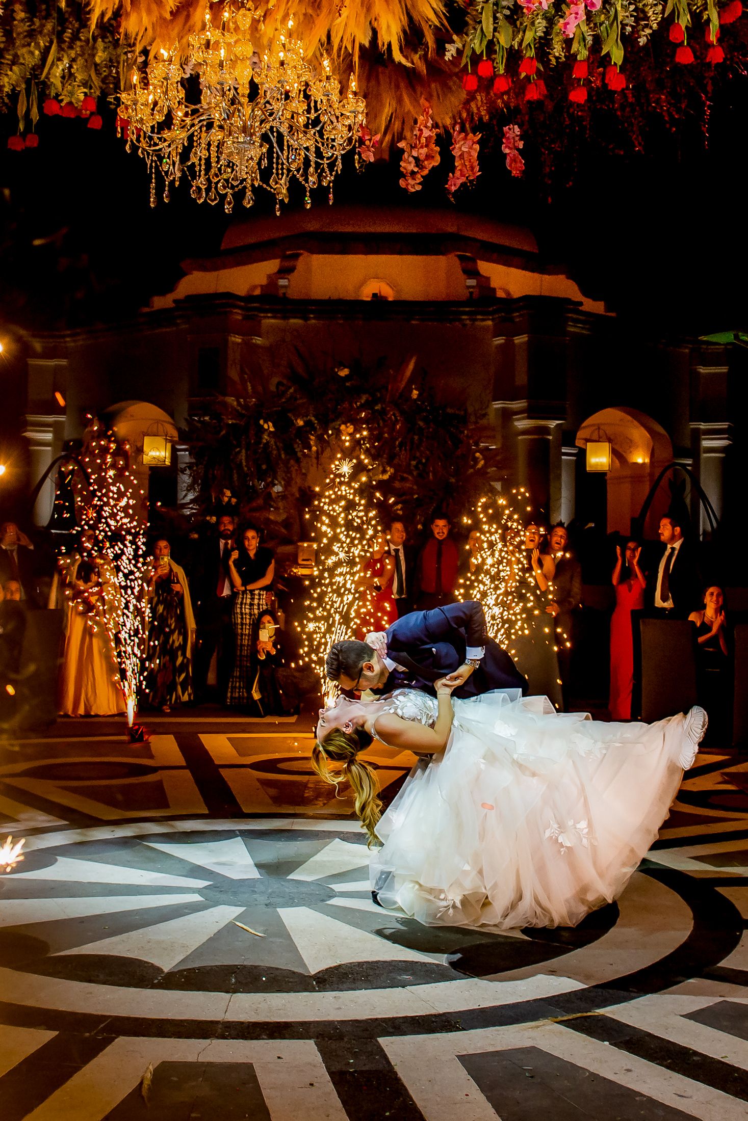 Romantic dance performance on a geometric patterned floor under golden chandeliers.