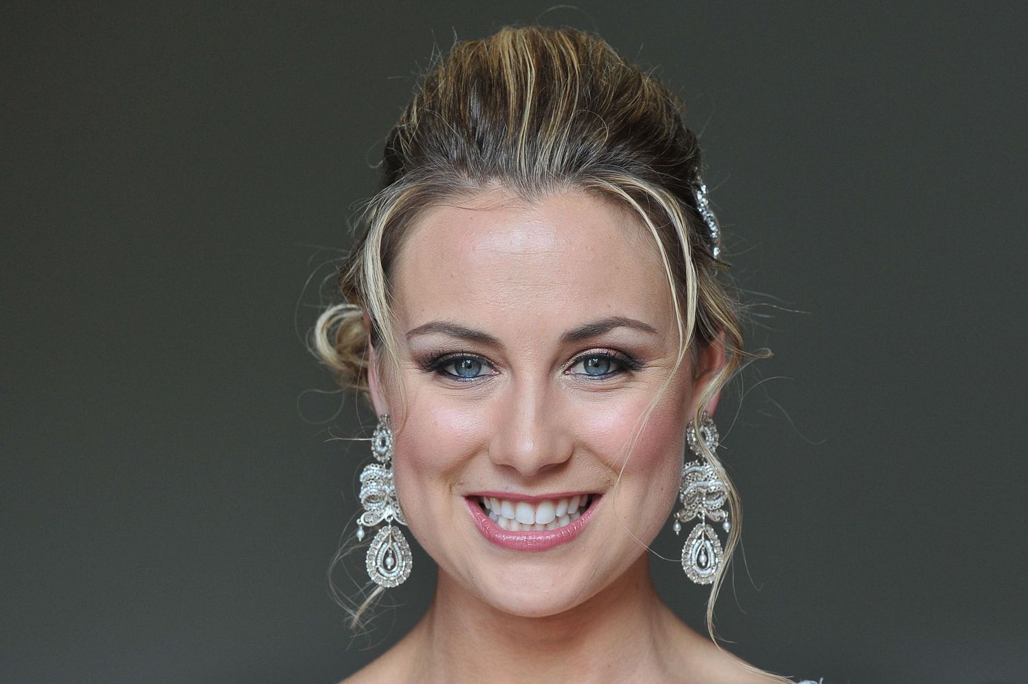 A bridal beauty portrait featuring glamorous makeup and crystal chandelier earrings.