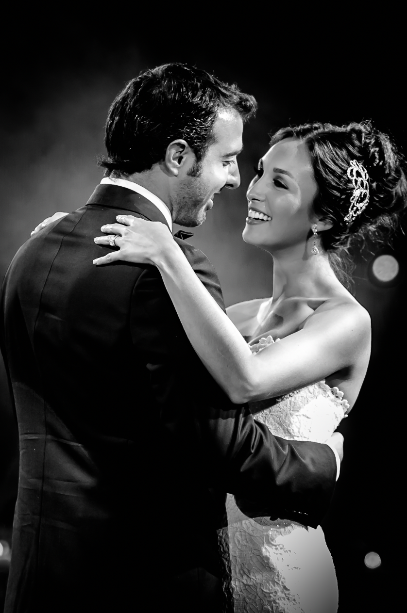 Intimate black and white portrait of couple dancing and laughing at their wedding celebration.