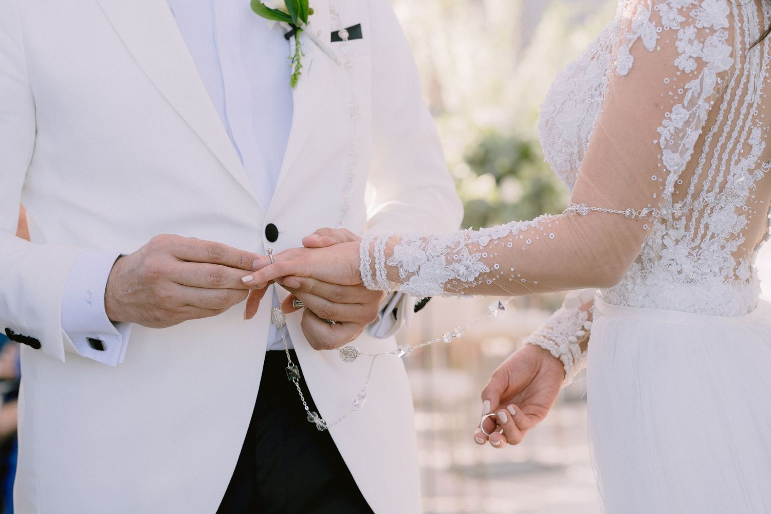 Bride and groom hold hands during their wedding ceremony against a bright outdoor backdrop.