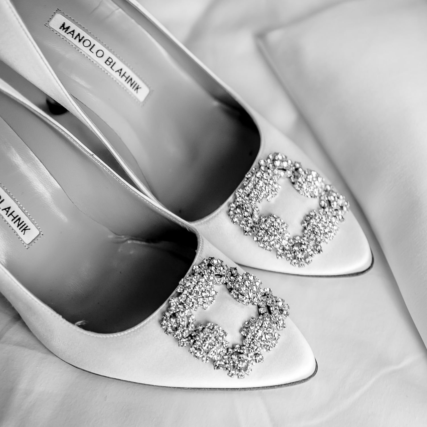 White bridal shoes with crystal butterfly embellishments photographed in black and white.