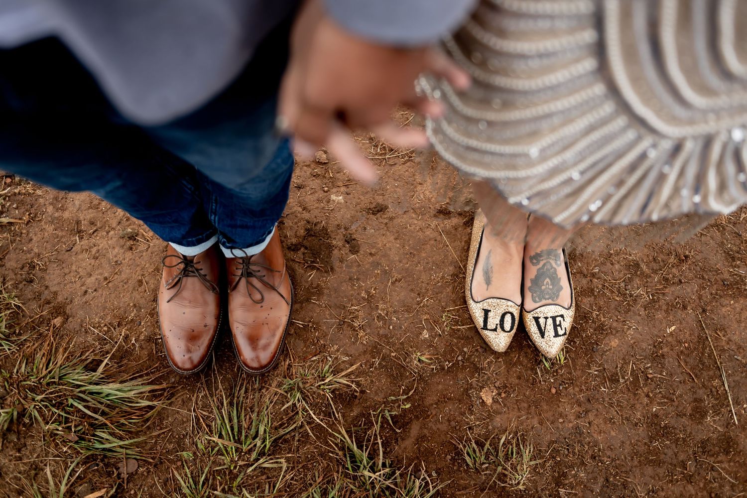 Close-up shot of wedding shoes standing on brown soil with a small 'LOVE' sign.