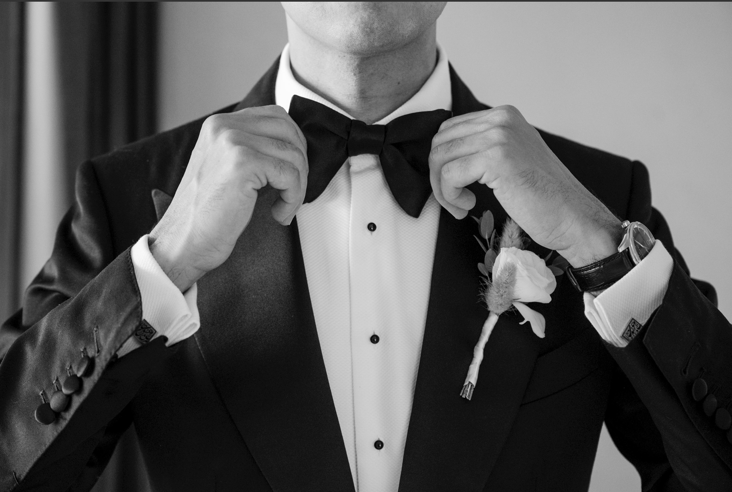A group of formally dressed people in black tuxedos and bow ties adjusting their bow ties in a synchronized manner.