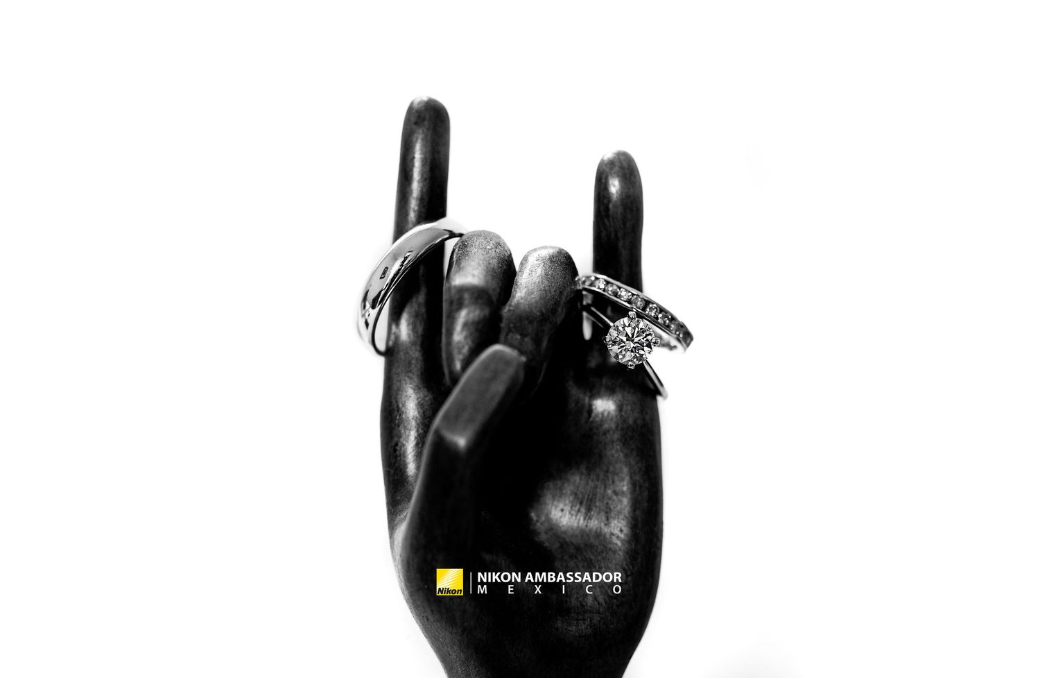 Black ceramic hand sculpture displaying engagement rings in rock and roll gesture.