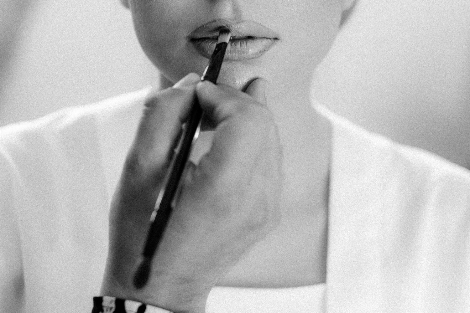 Close-up of someone applying makeup with a brush in black and white.