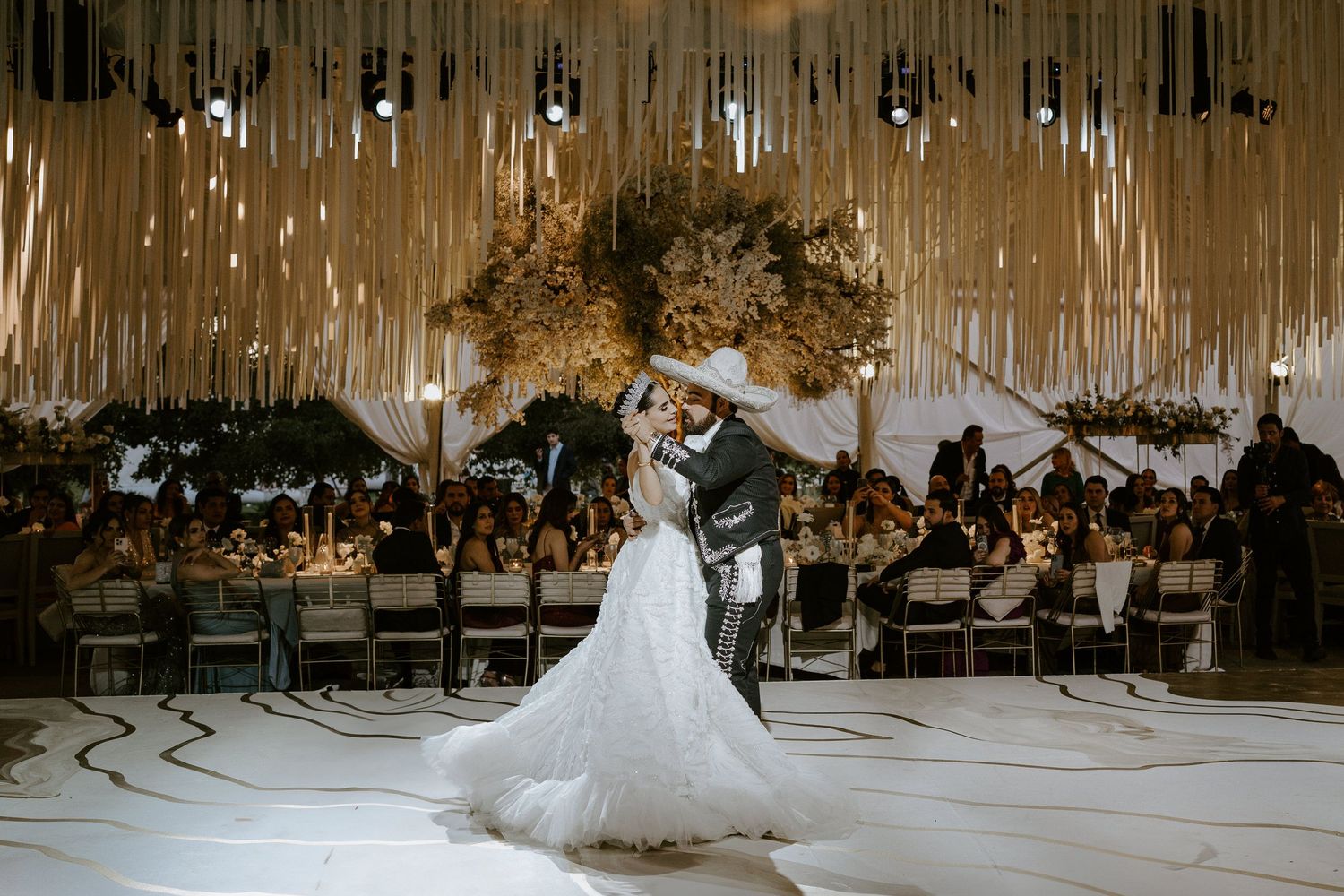 Wedding reception venue features dramatic hanging installations and white dance floor.
