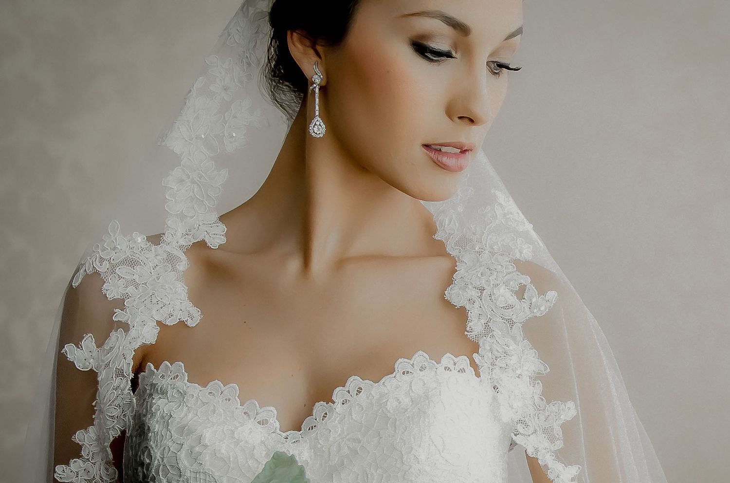 Delicate lace detail of wedding dress and veil in soft natural light.