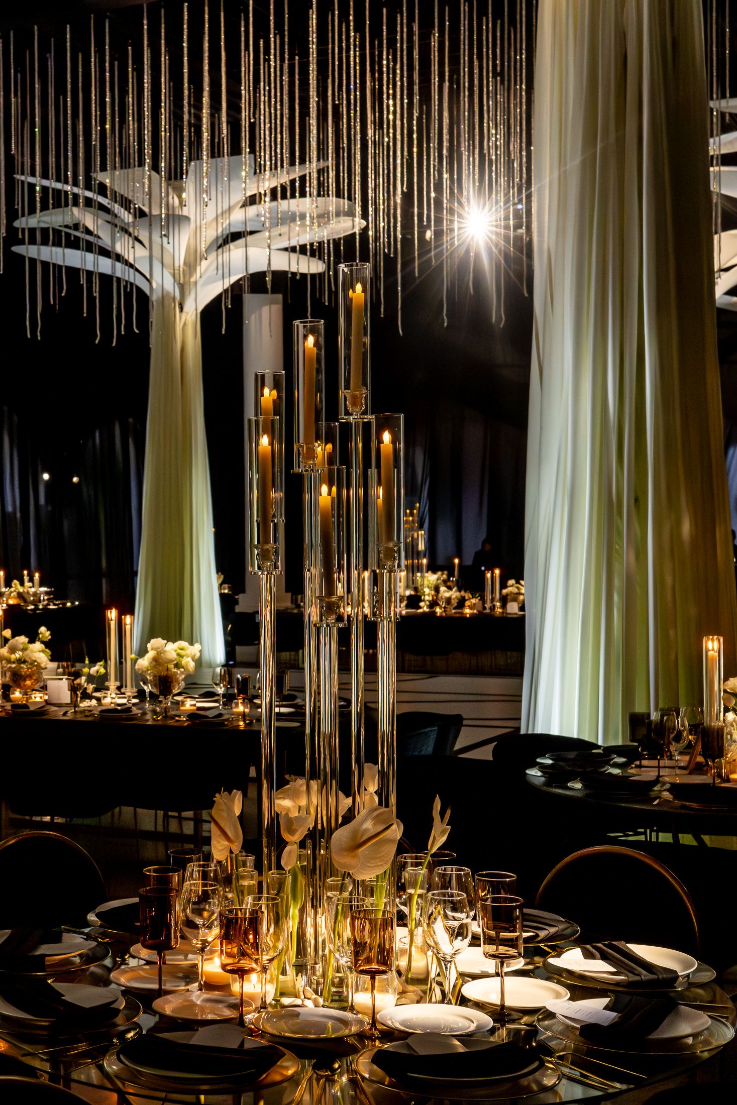 Intimate dining setup with hanging crystal strands and glowing candlelight creating dramatic ambiance.