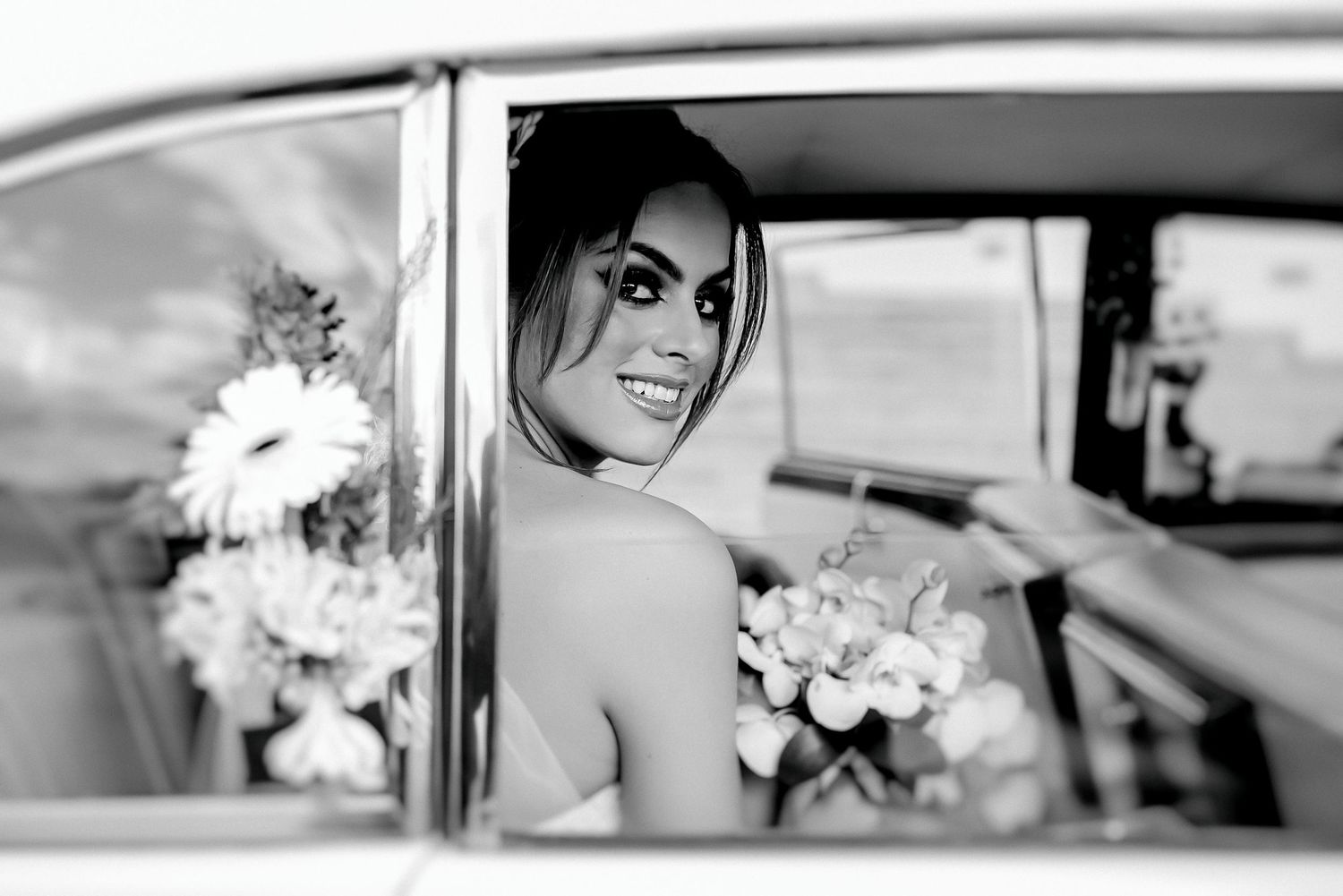 Black and white wedding photography sequence showing romantic moments with flowers and a vintage car.