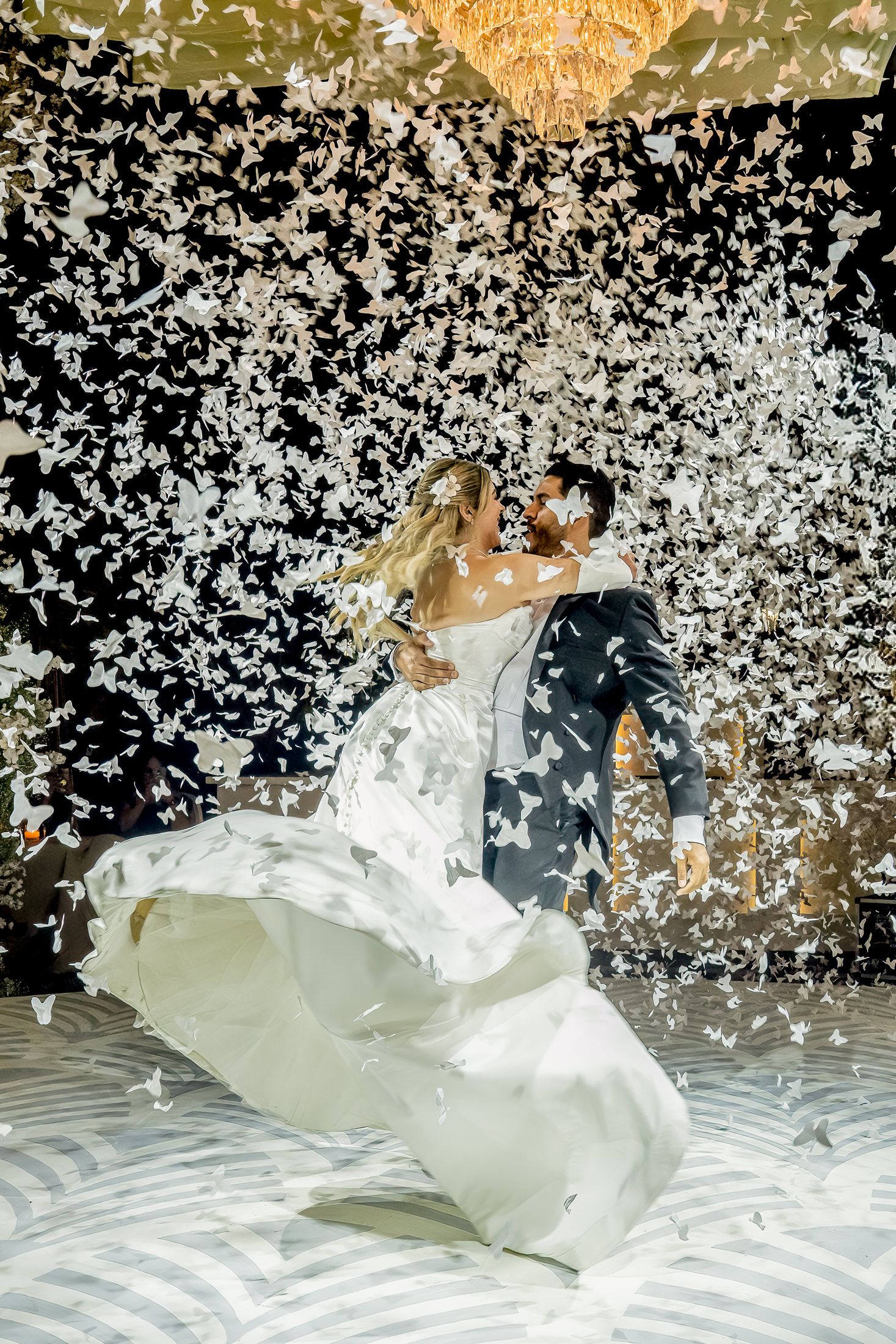 A dramatic wedding dance captured with swirling confetti and a flowing white dress.
