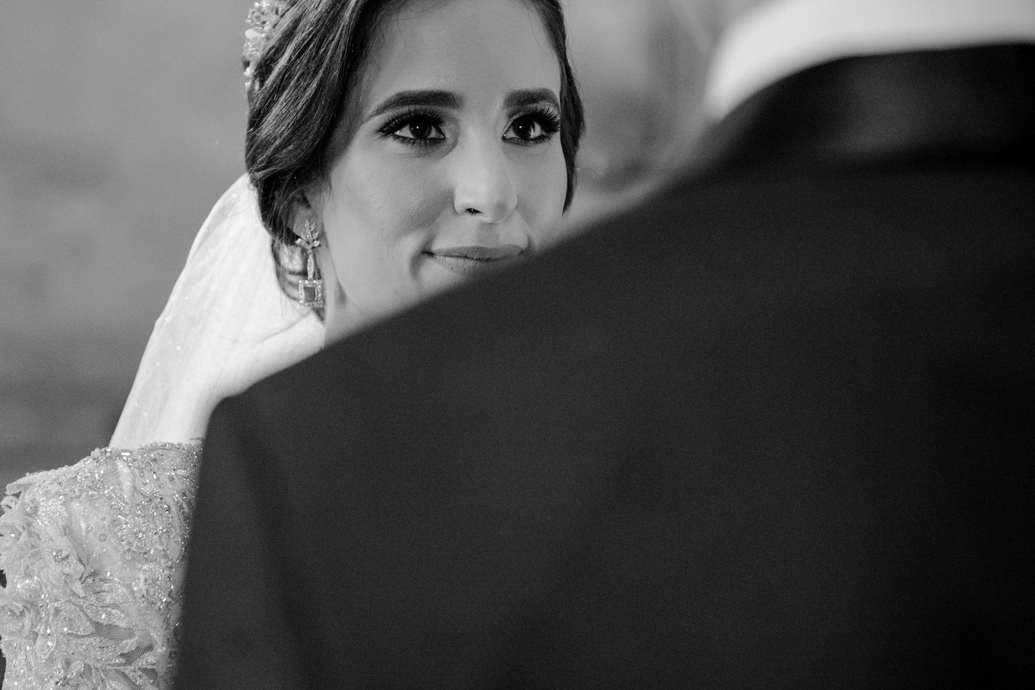 Black and white wedding photo of a bride in veil and tiara gazing lovingly at groom in suit.