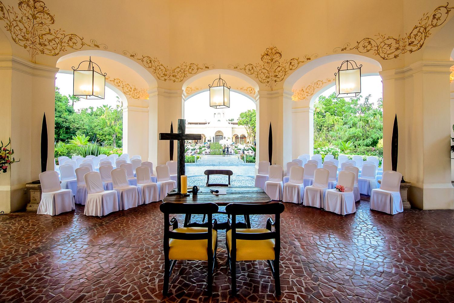 Elegant chapel venue with white chairs, golden arches, and a cross for ceremonies.