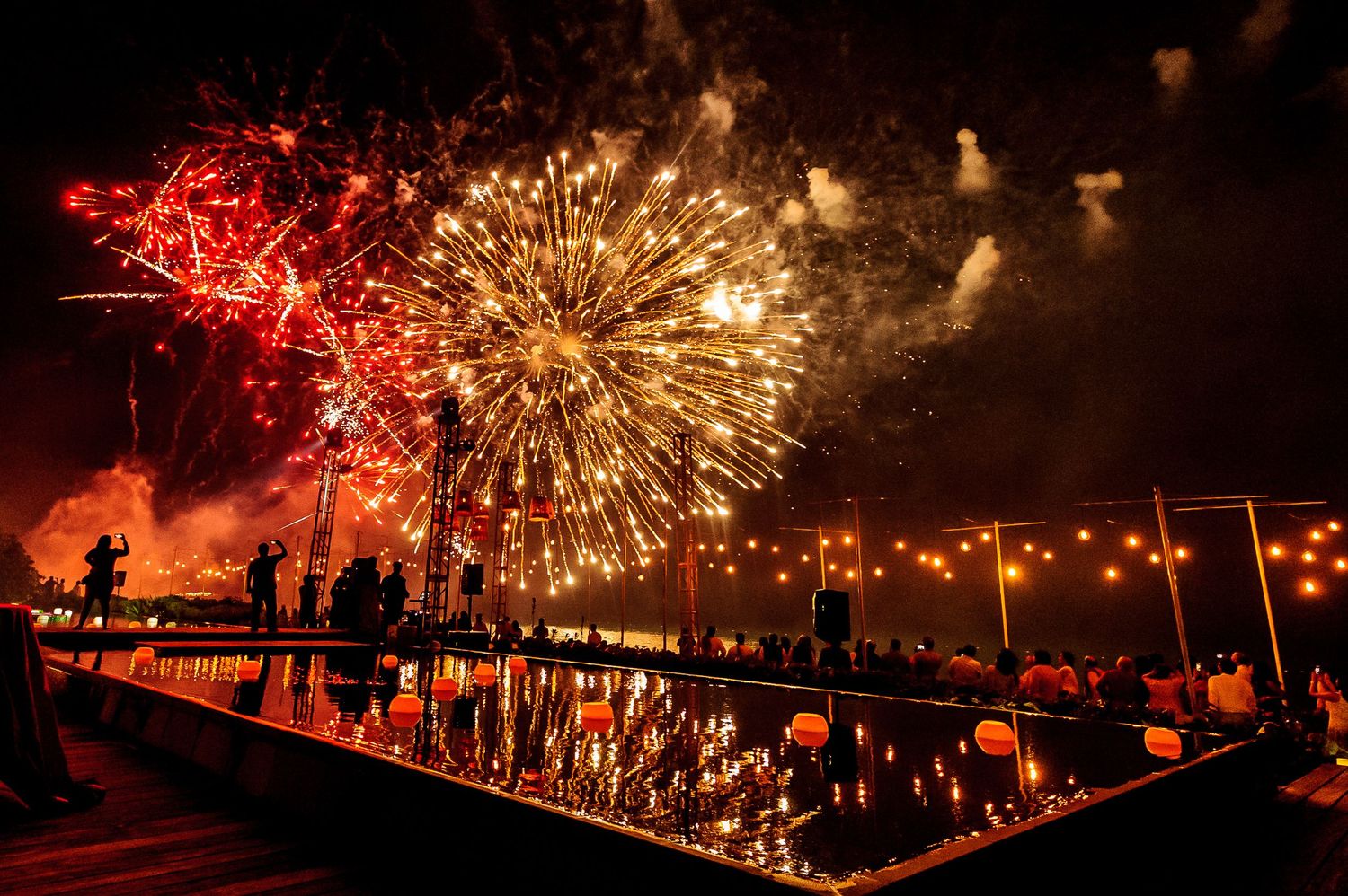 Spectacular fireworks display illuminating the night sky in red and gold bursts.