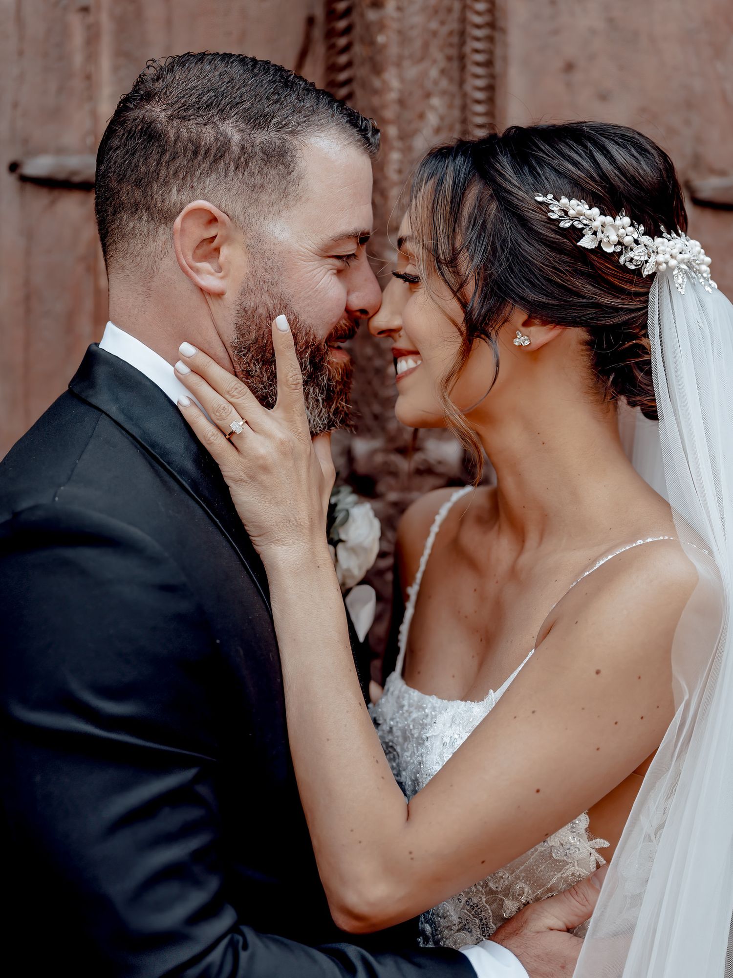 A romantic wedding kiss between a couple in formal attire with the bride wearing a white veil and lace dress.