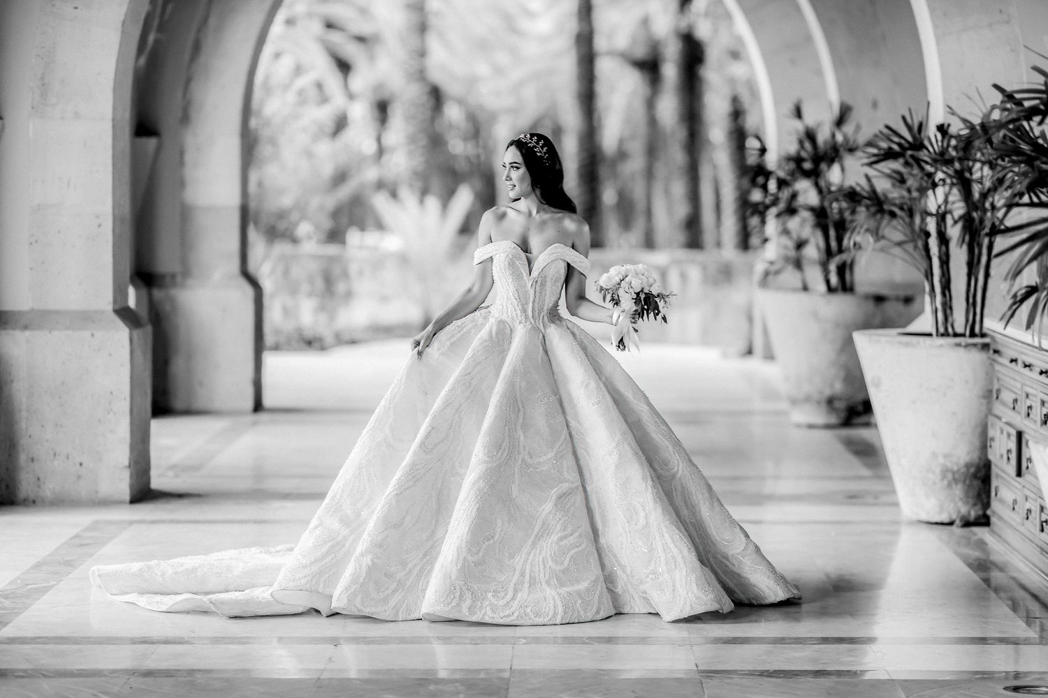 Dramatic side view of princess wedding gown with full skirt and train in outdoor setting.