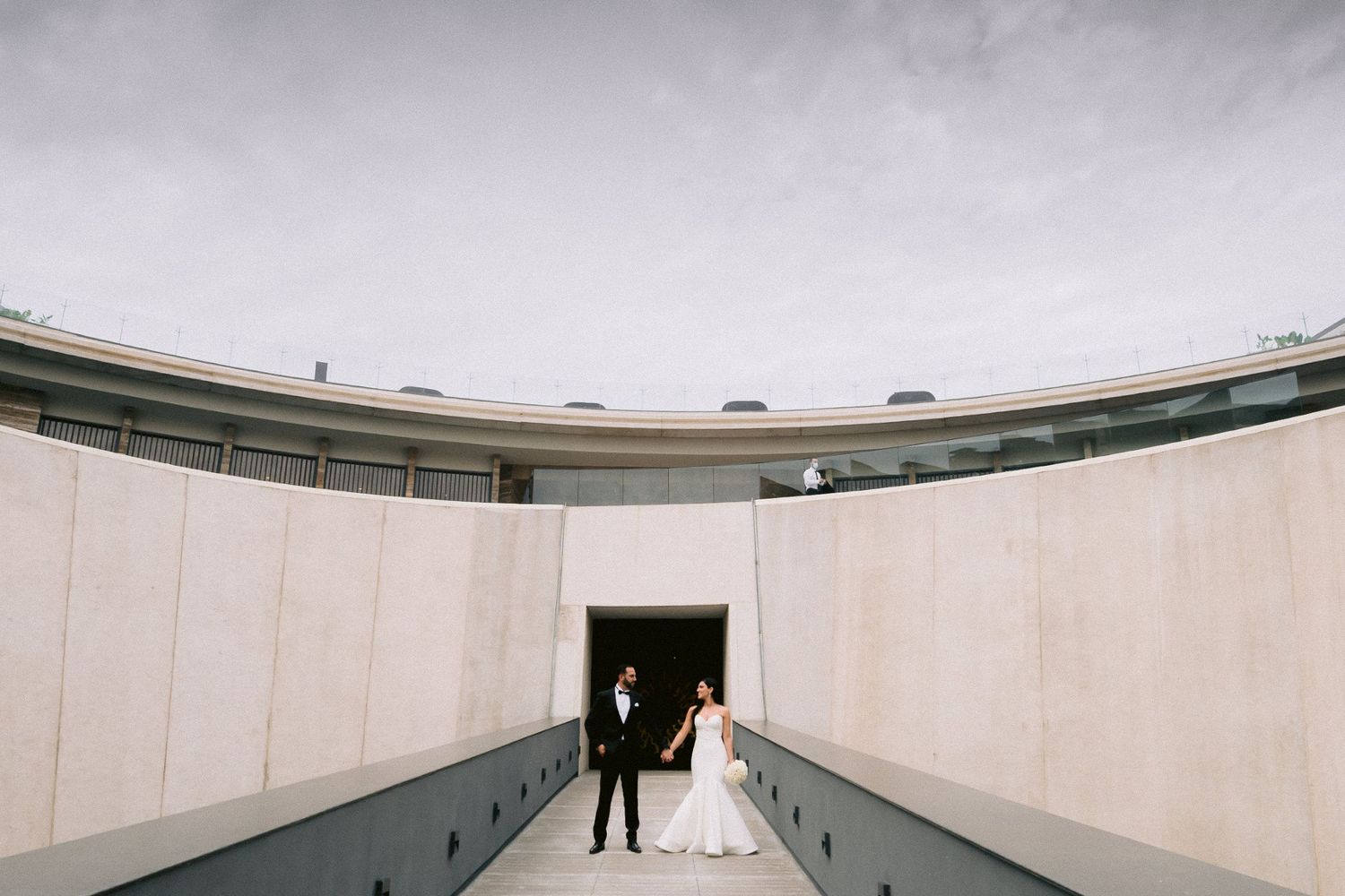 Minimalist wedding photo in a long white corridor with dramatic perspective.