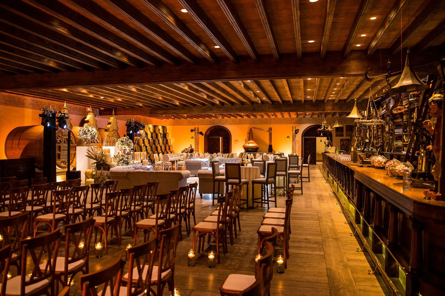 Warmly lit restaurant interior with wooden chairs, long bar, and arched alcoves creating an inviting dining atmosphere.
