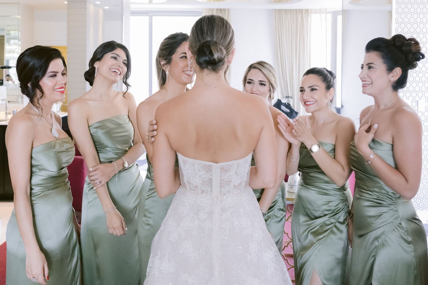 Wedding party in sage green dresses sharing joyful moments together.