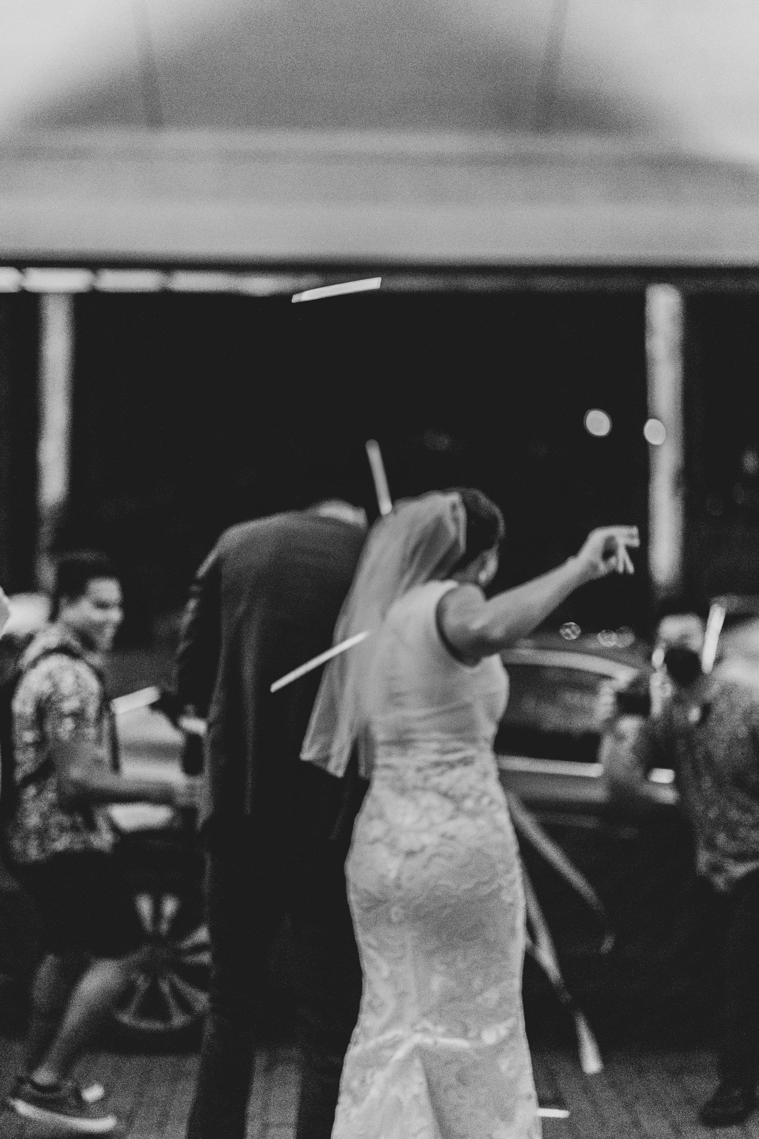 A bride in a white lace wedding dress dances joyfully on the dance floor during a reception celebration.