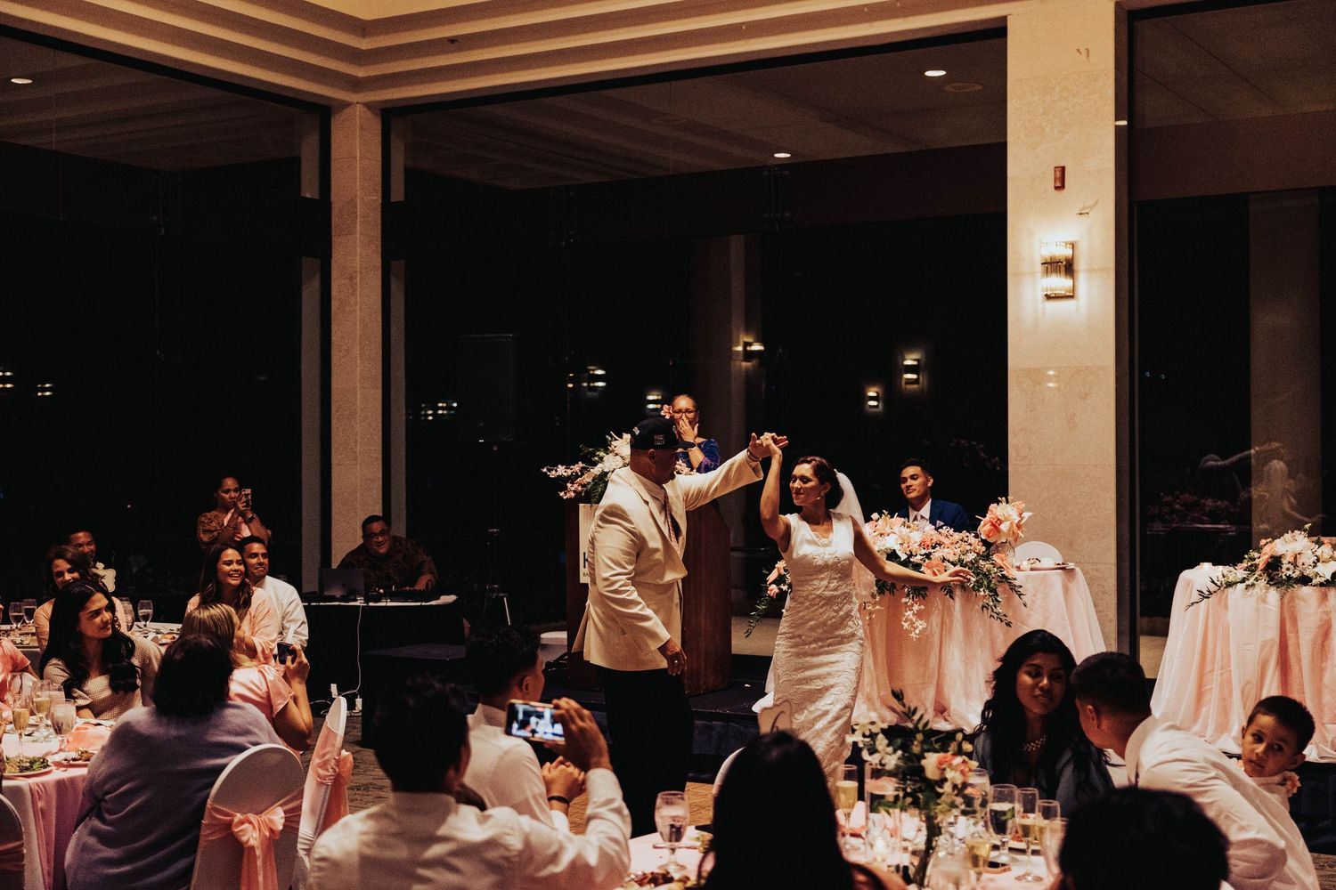 Wedding guests in white dresses dance together during an evening reception celebration.