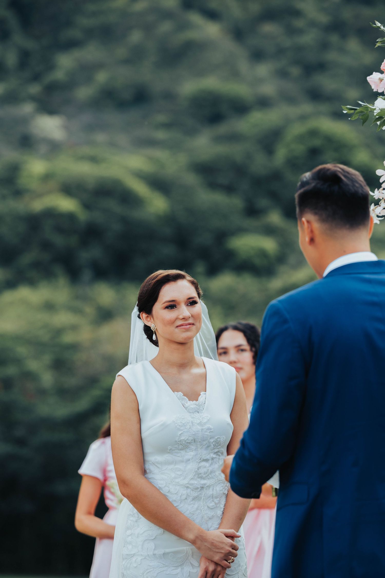 A bride and groom share an intimate moment during their outdoor wedding ceremony with lush greenery in the background.