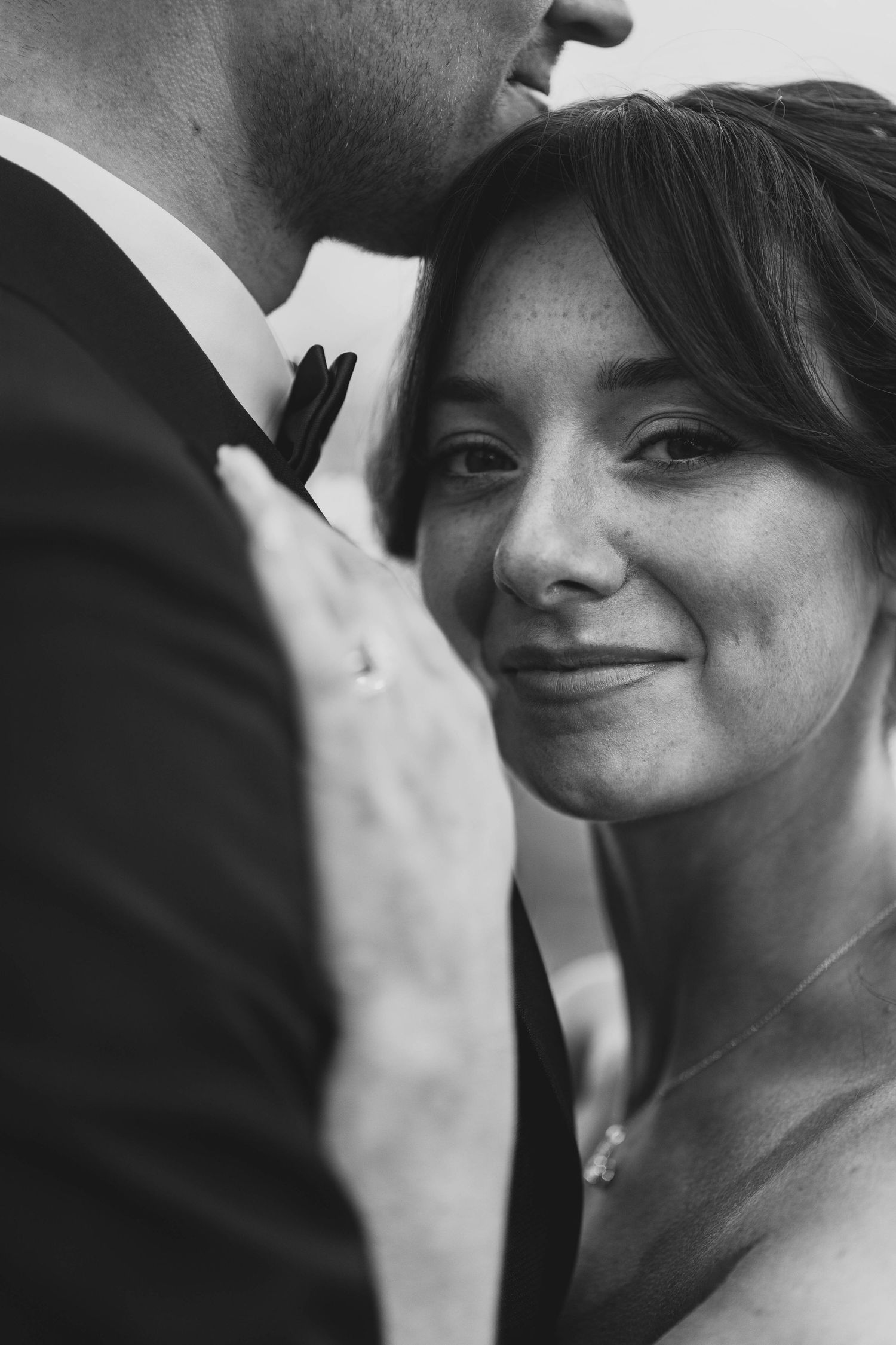 A sequence of black and white close-up photos showing intimate moments between a couple during a wedding.