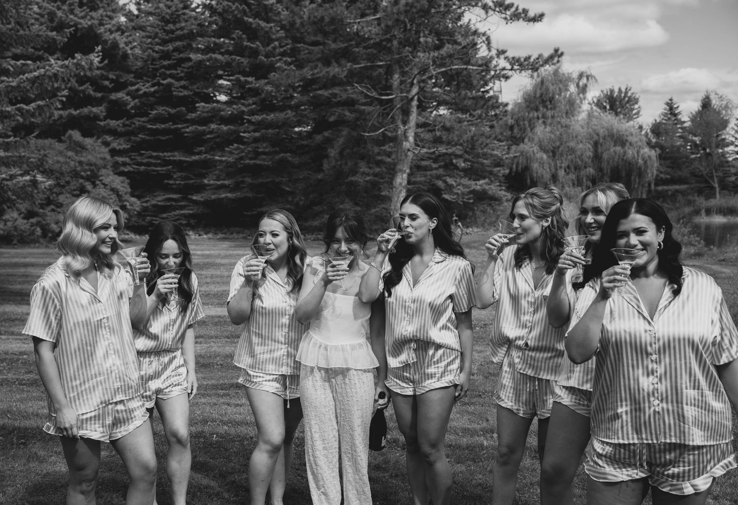 A black and white photograph showing a group of people standing together outdoors in casual summer attire.