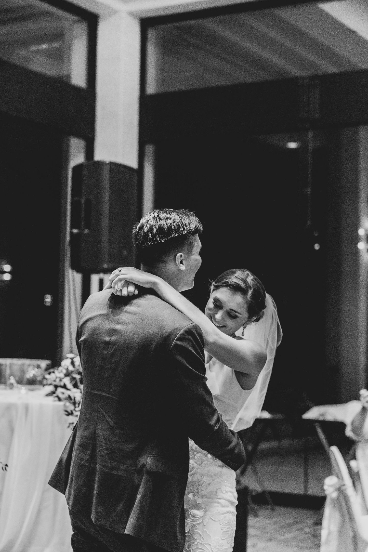 A bride and groom share their first dance at their wedding reception in black and white photography.