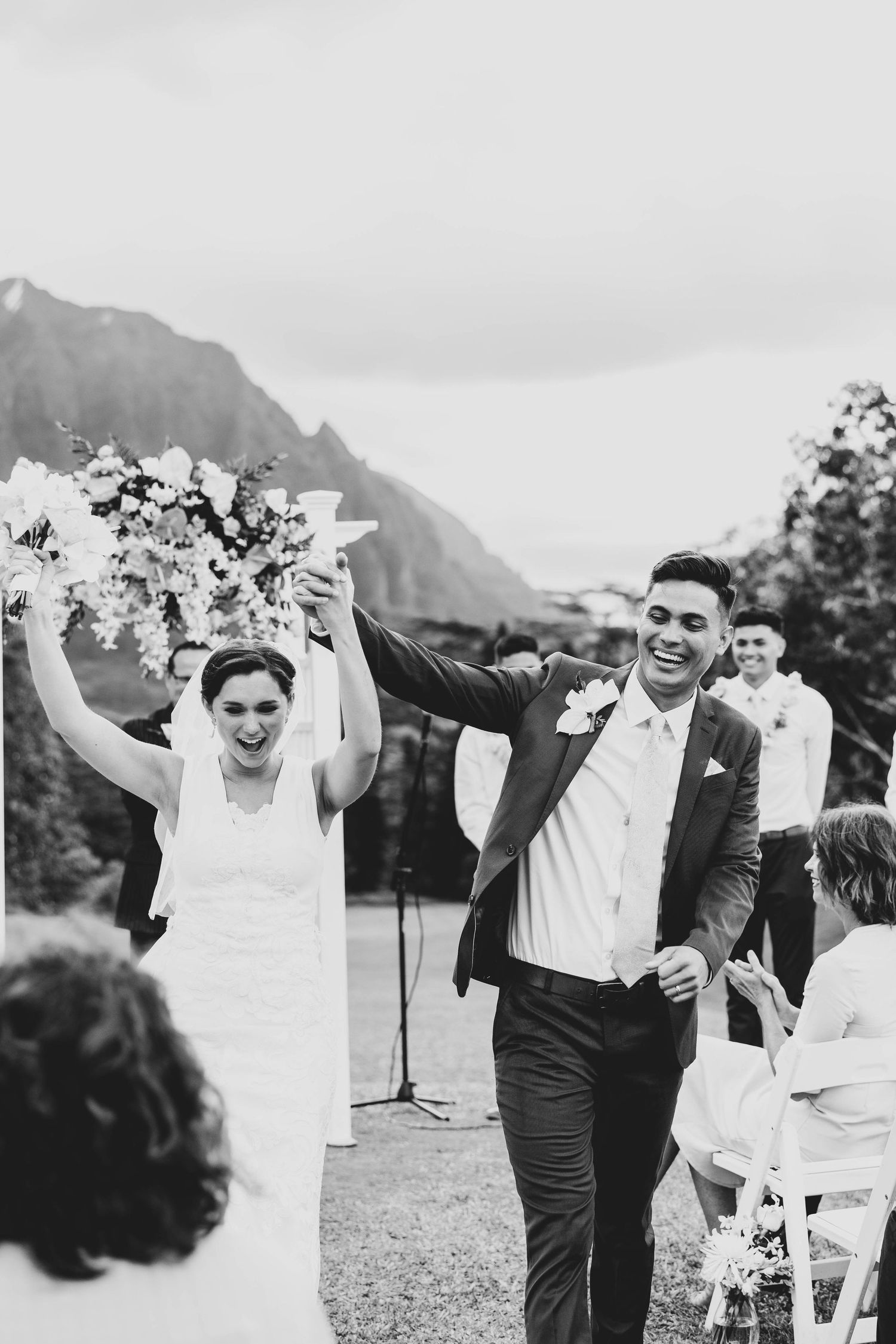 A joyful celebration captured in black and white as people dance outdoors with mountains in the background.