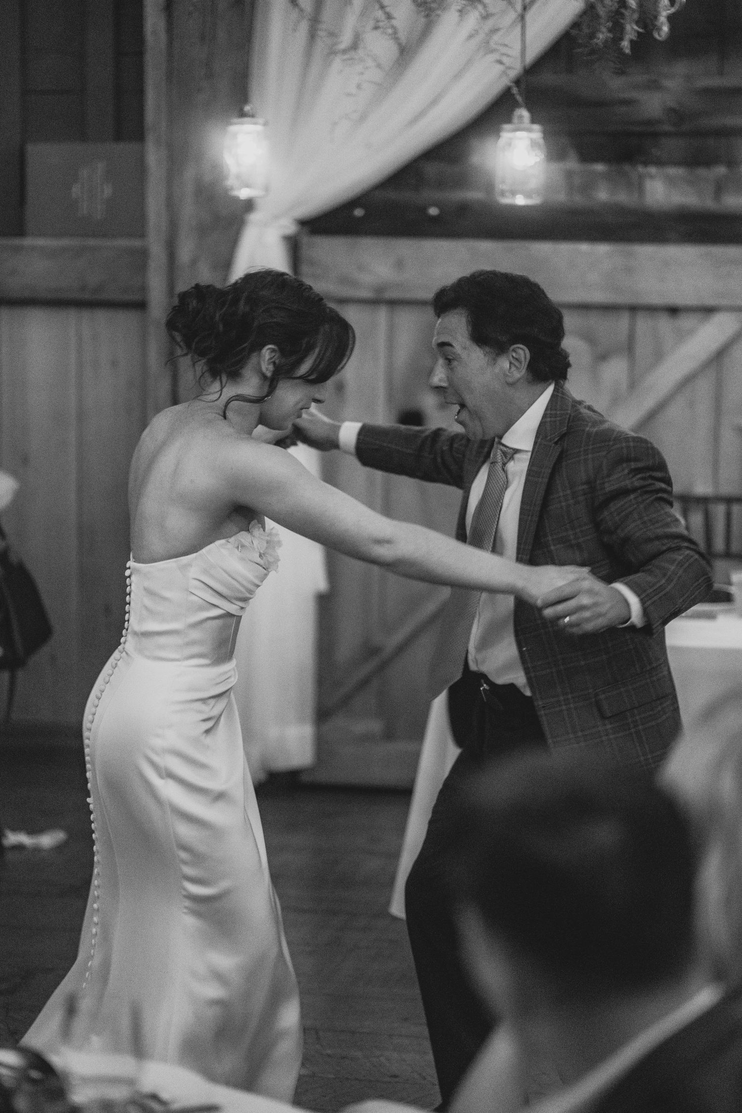 A couple performs an elegant dance move in a ballroom with the woman in white and man in dark suit.