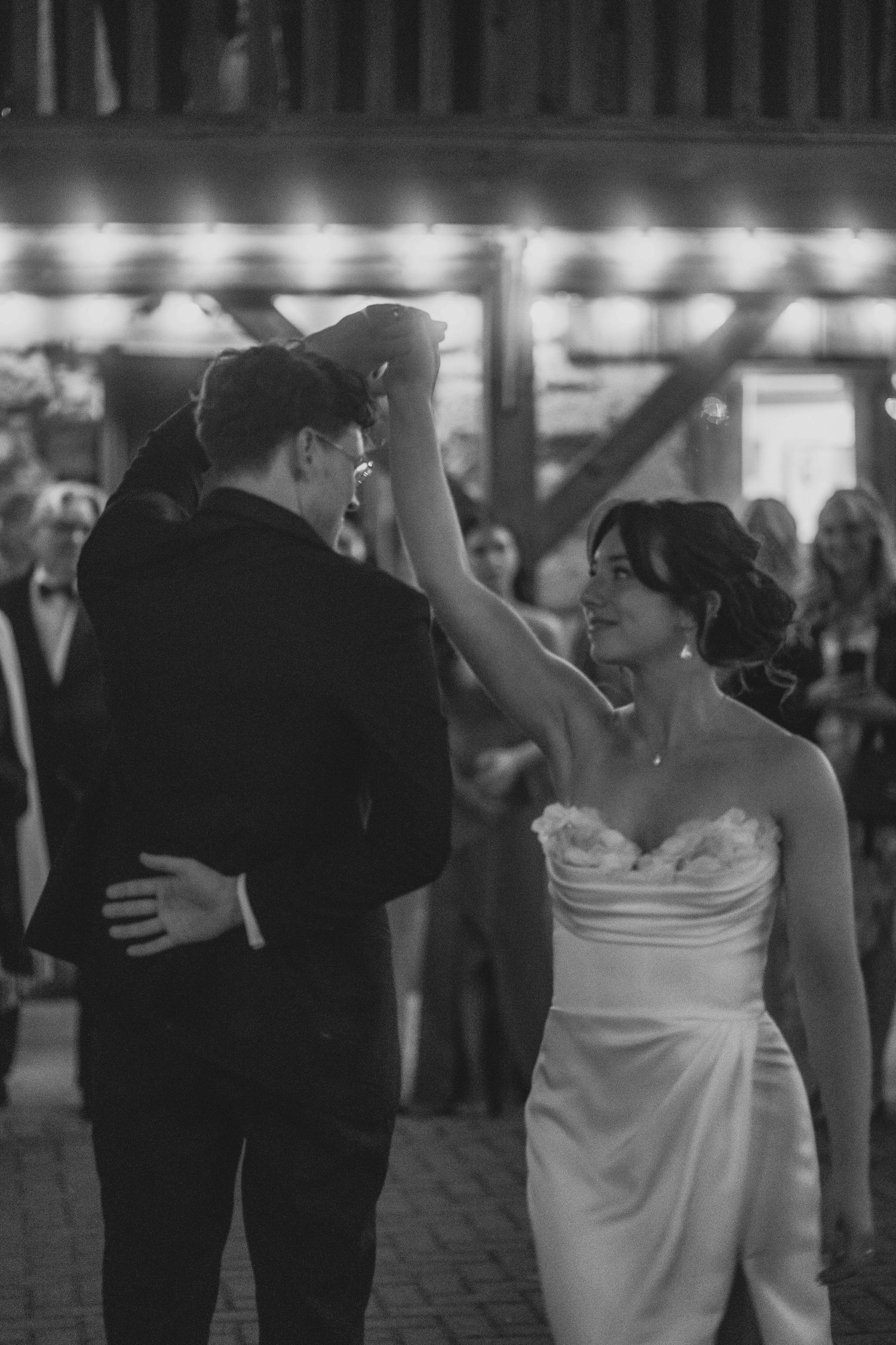 A couple shares their first dance at their wedding reception, with the bride in a white strapless gown and groom in black suit.