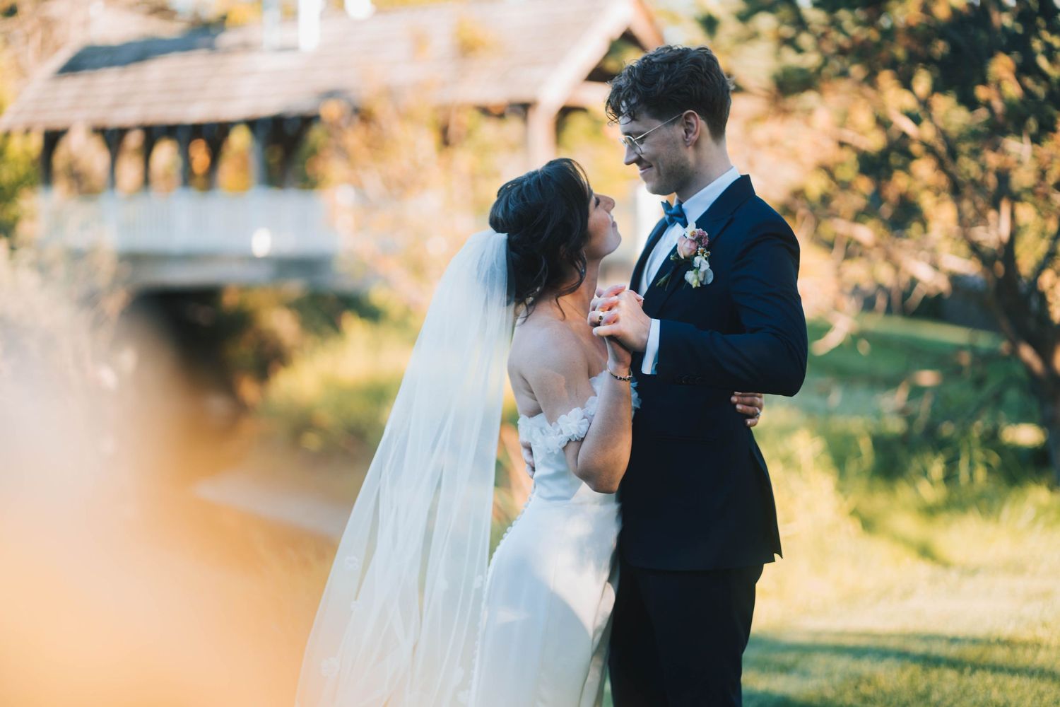 Bride and groom embrace in golden autumn light during outdoor wedding portraits.