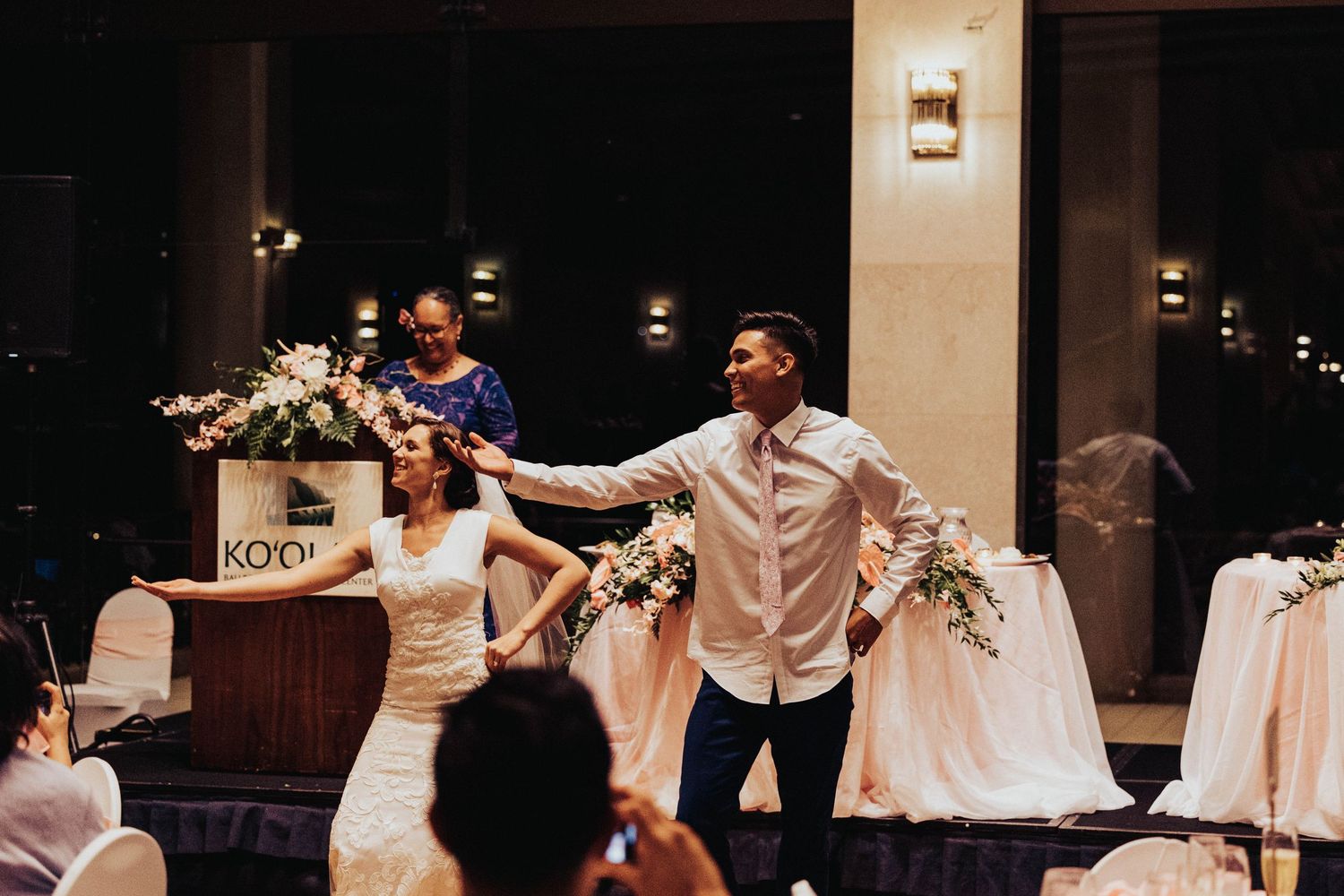 A bride and groom share their first dance at an elegant indoor wedding reception with guests watching.