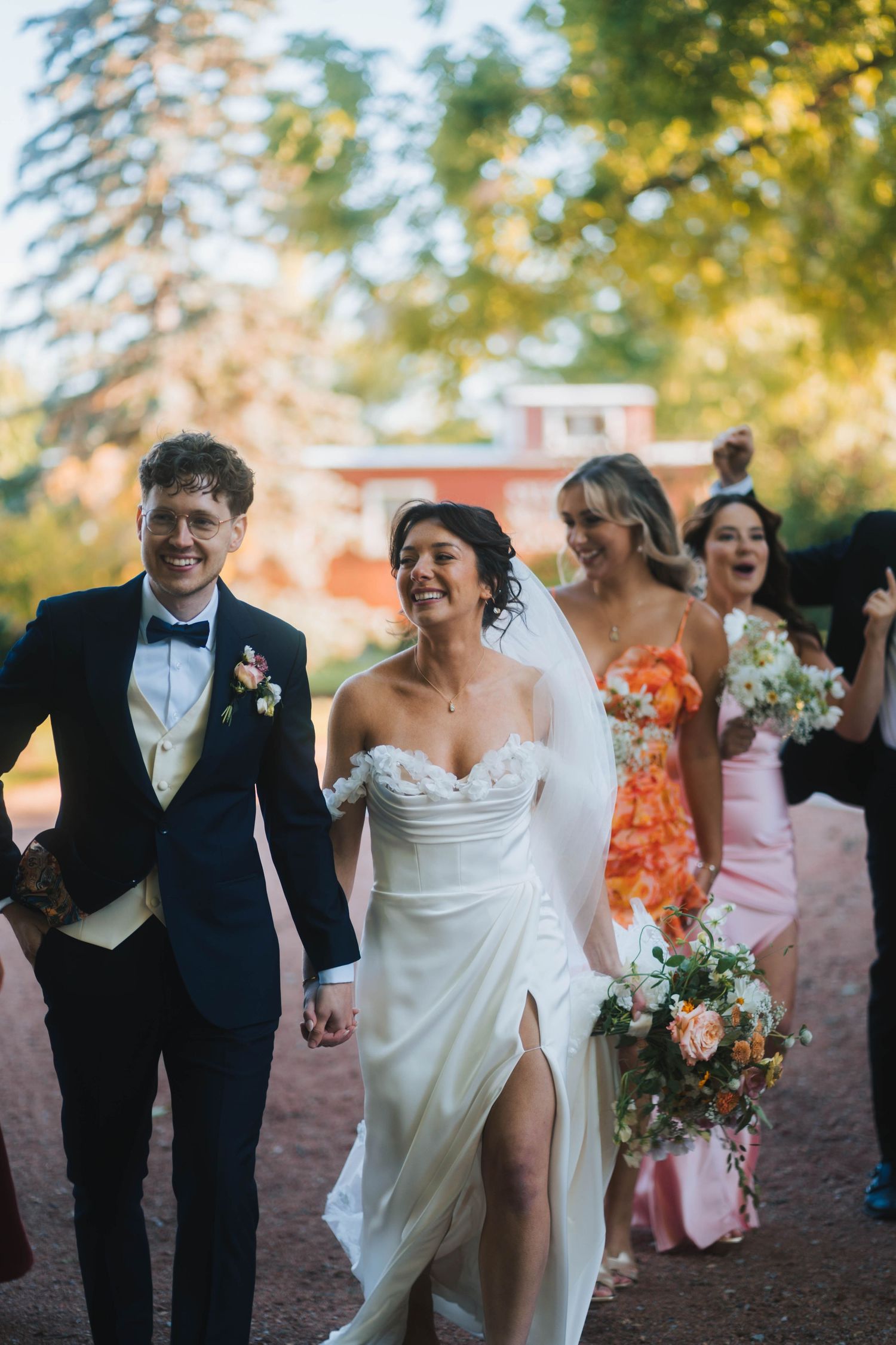 Wedding party members walking and laughing together outdoors during autumn celebration.