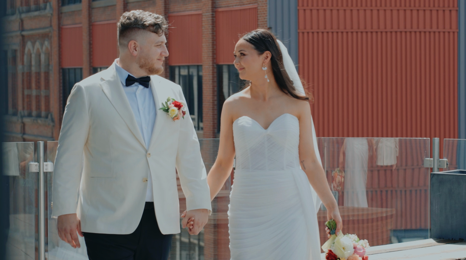 A couple shares romantic moments in a modern urban setting while wearing elegant wedding attire.