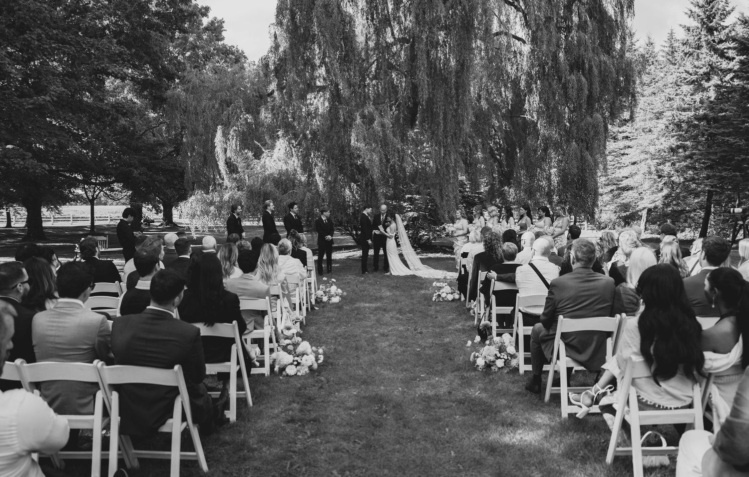 A series of black and white photos showing an outdoor wedding ceremony setup with rows of white chairs on a lawn.