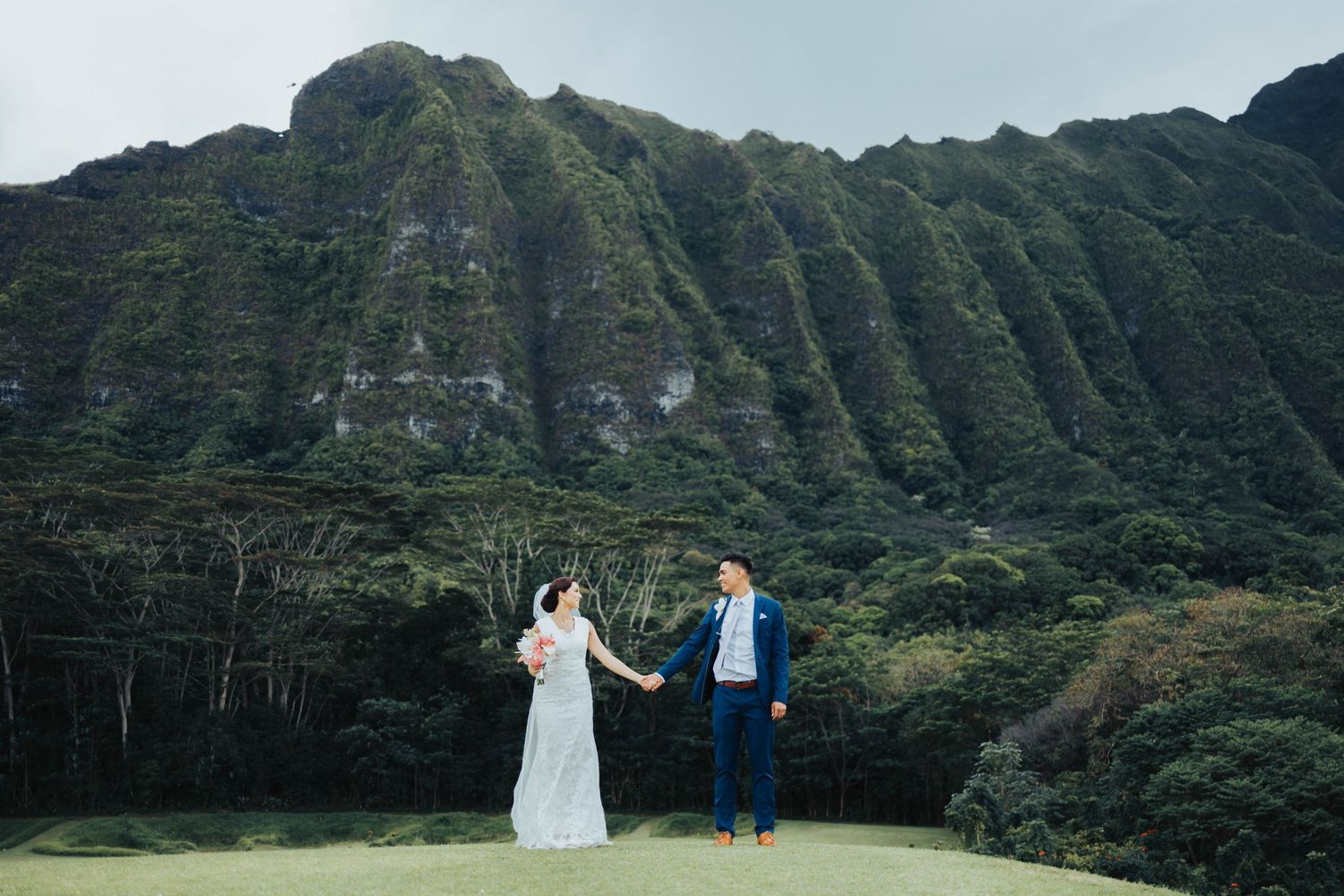 Wedding ceremony with dramatic mountain backdrop in a lush Hawaiian landscape.