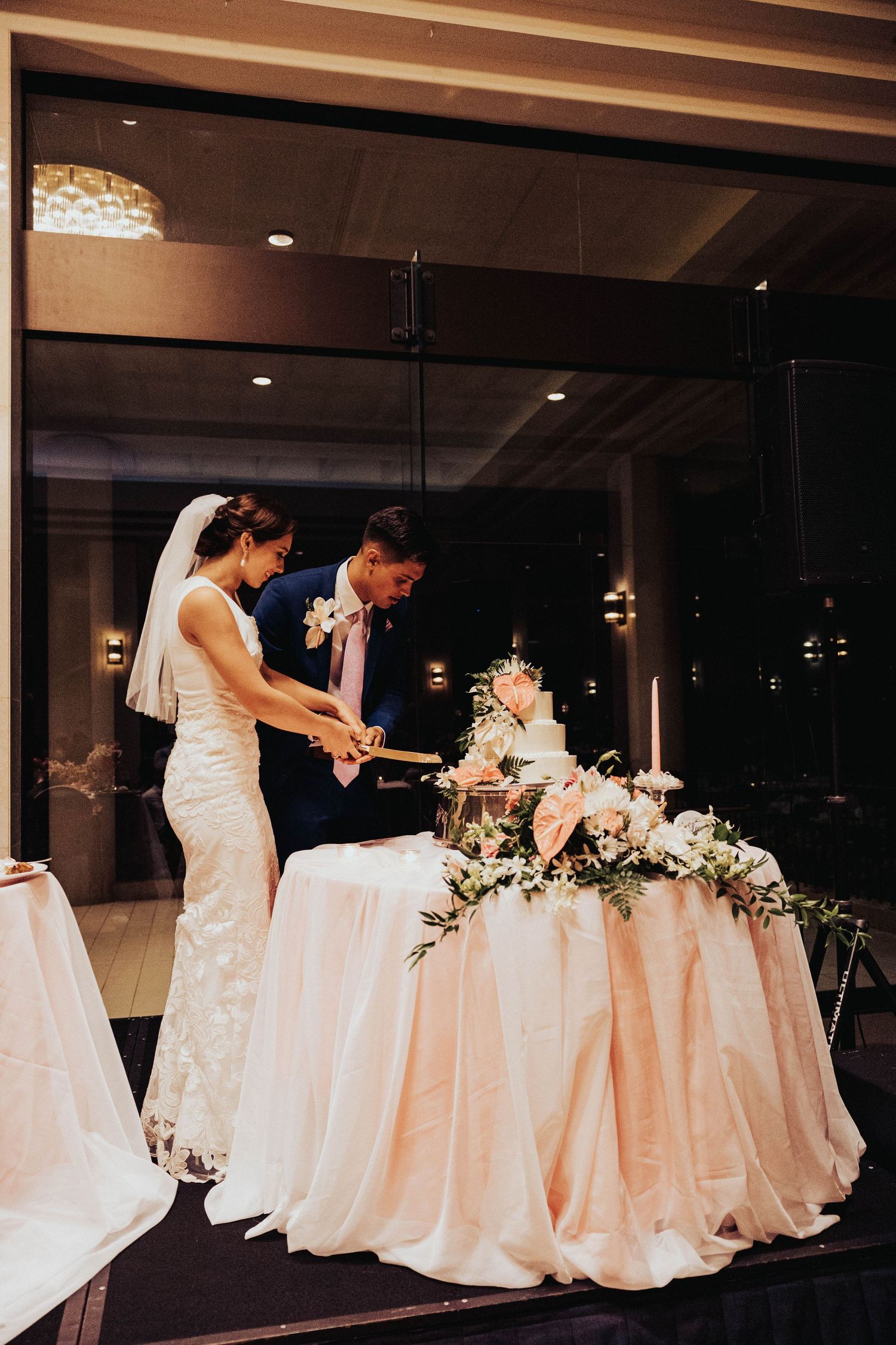 Wedding party members gather at an elegant reception table decorated with floral arrangements and white linens.