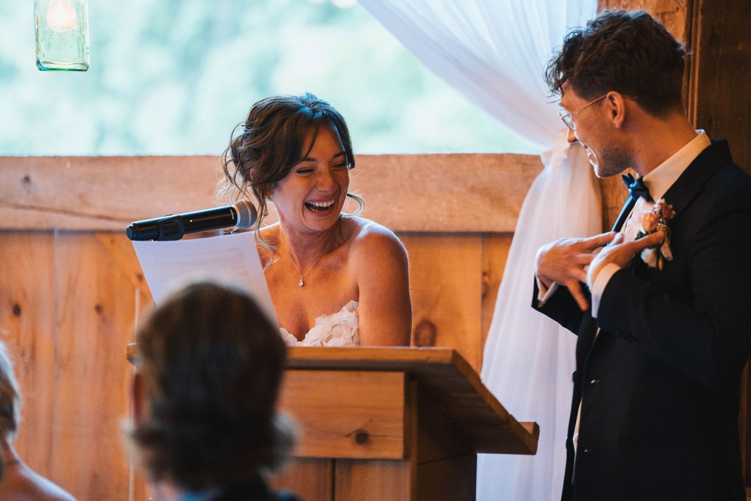 A couple shares a joyful moment together during their rustic barn wedding ceremony.