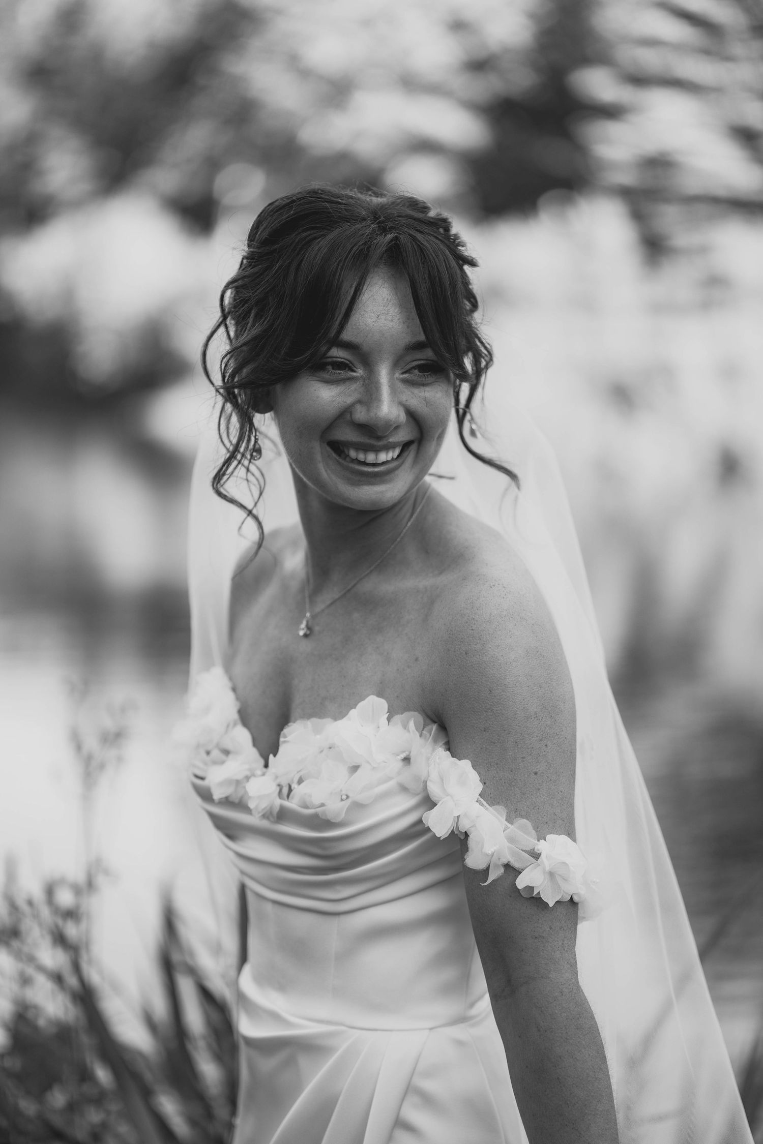 Black and white wedding portrait series showing joyful moments with white orchids and flowing veil details.