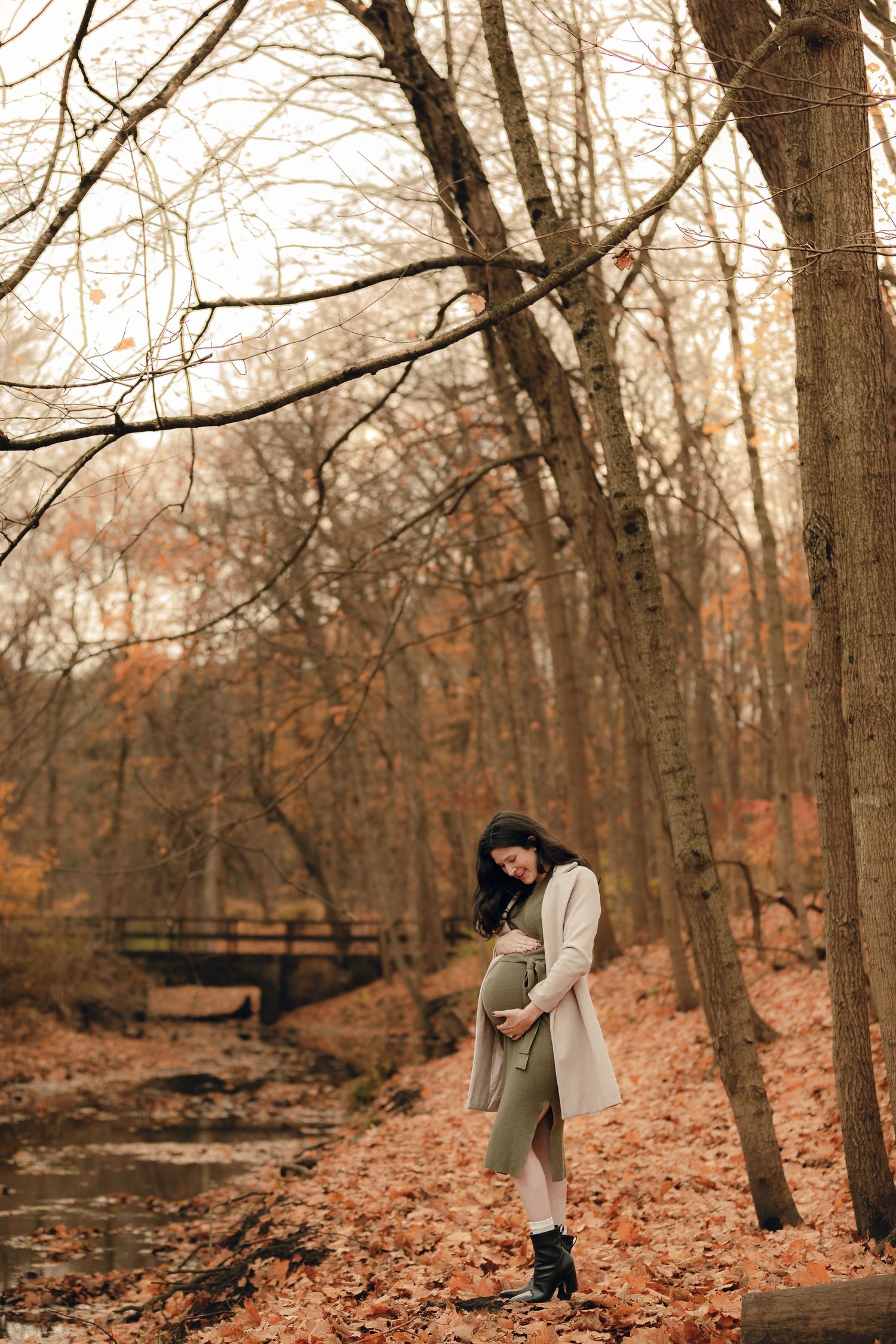 Family exploring autumn woods near wooden bridge and stream.