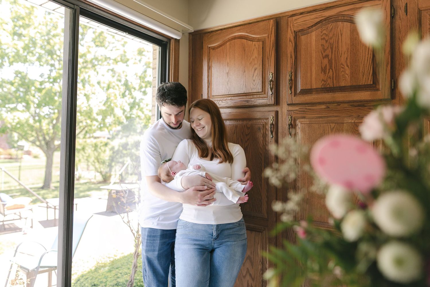 Sunlit kitchen scene with family members sharing a tender moment.