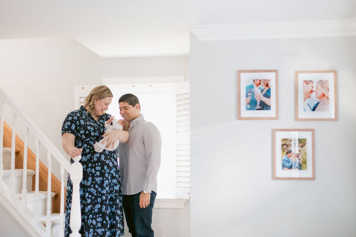 Couple sharing intimate moment by staircase with floral artwork on wall.