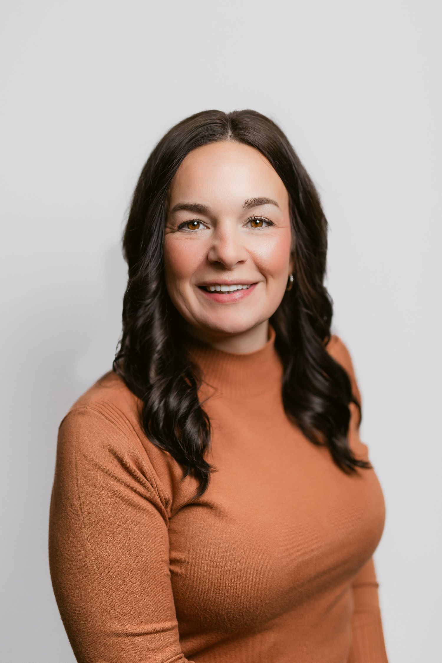 Warm professional portraits of person in rust-colored top against neutral background.