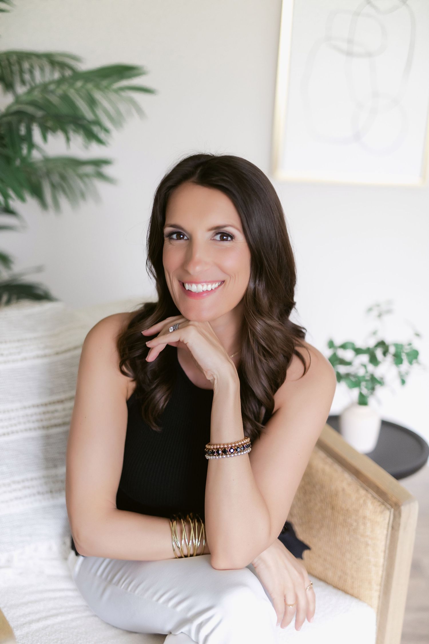 Professional headshots showing bright smiles in a modern white studio setting with tropical plants.