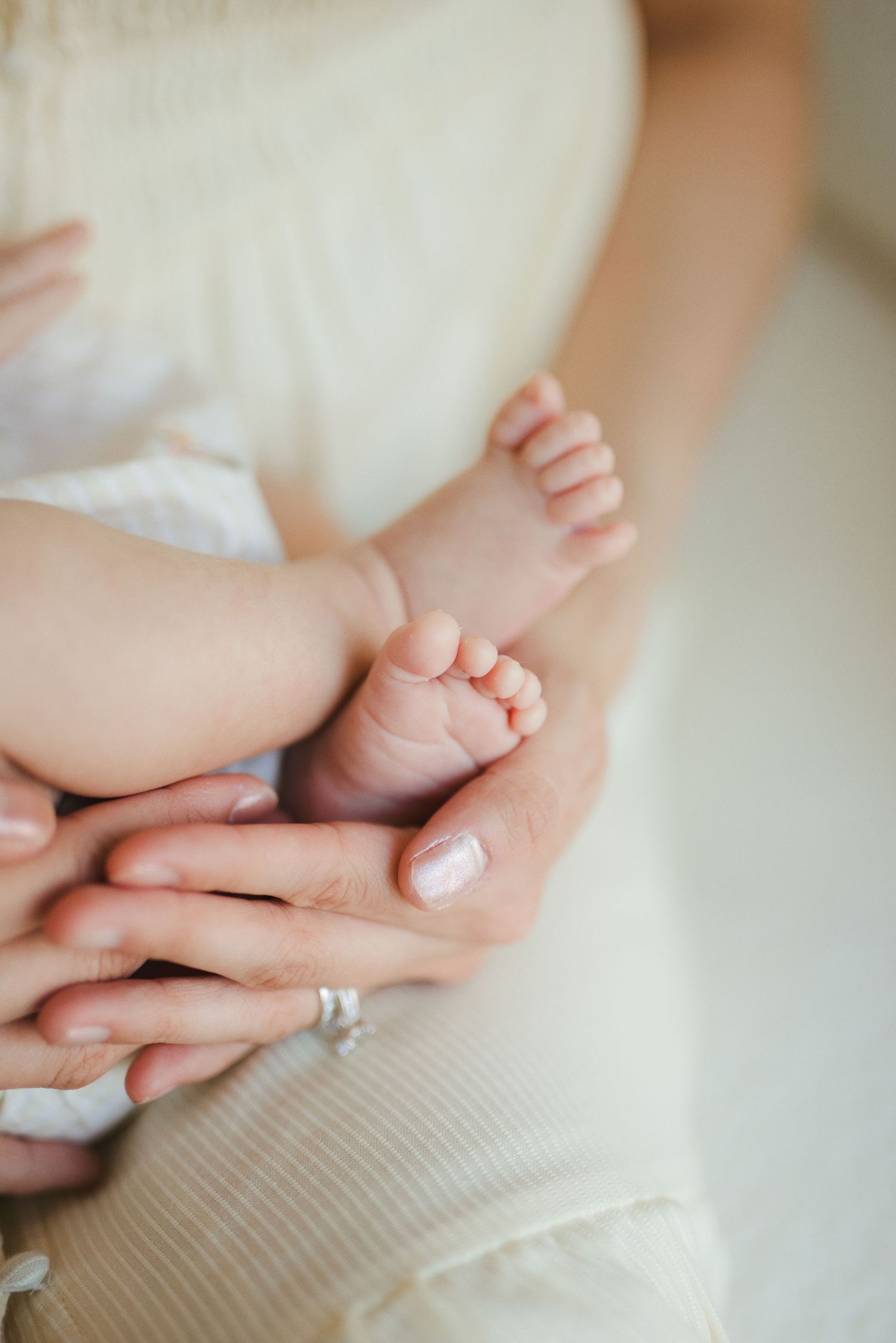 Close-up of a mother's hands gently cradling her newborn baby's tiny feet, symbolizing love and new life.
