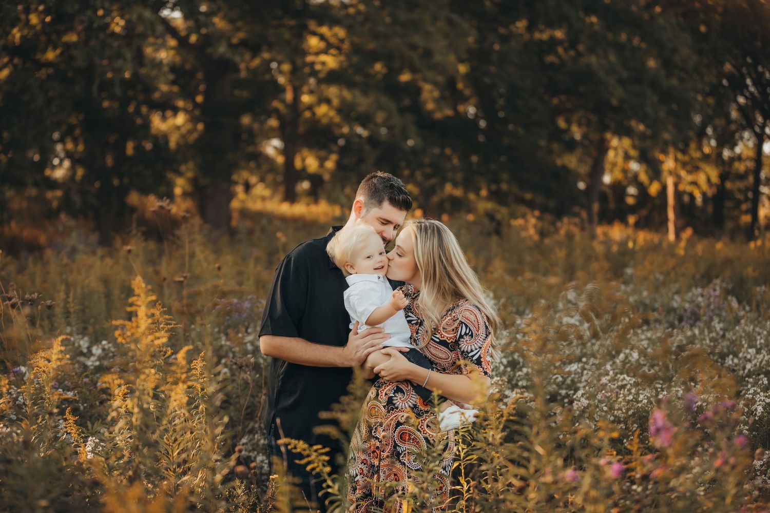 A family enjoys a warm autumn sunset together at a Christmas tree farm with golden light filtering through evergreens.